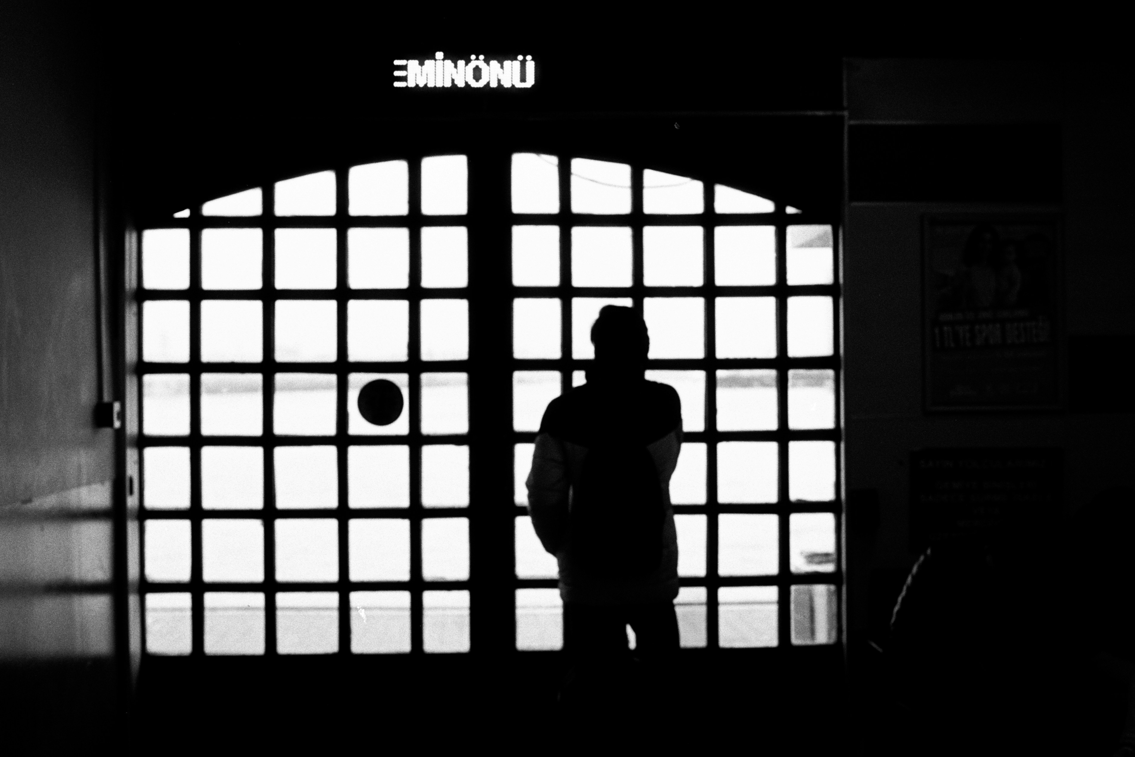 Silhouette of a person standing by a large window (Photo by ONUR KURT on Unsplash)