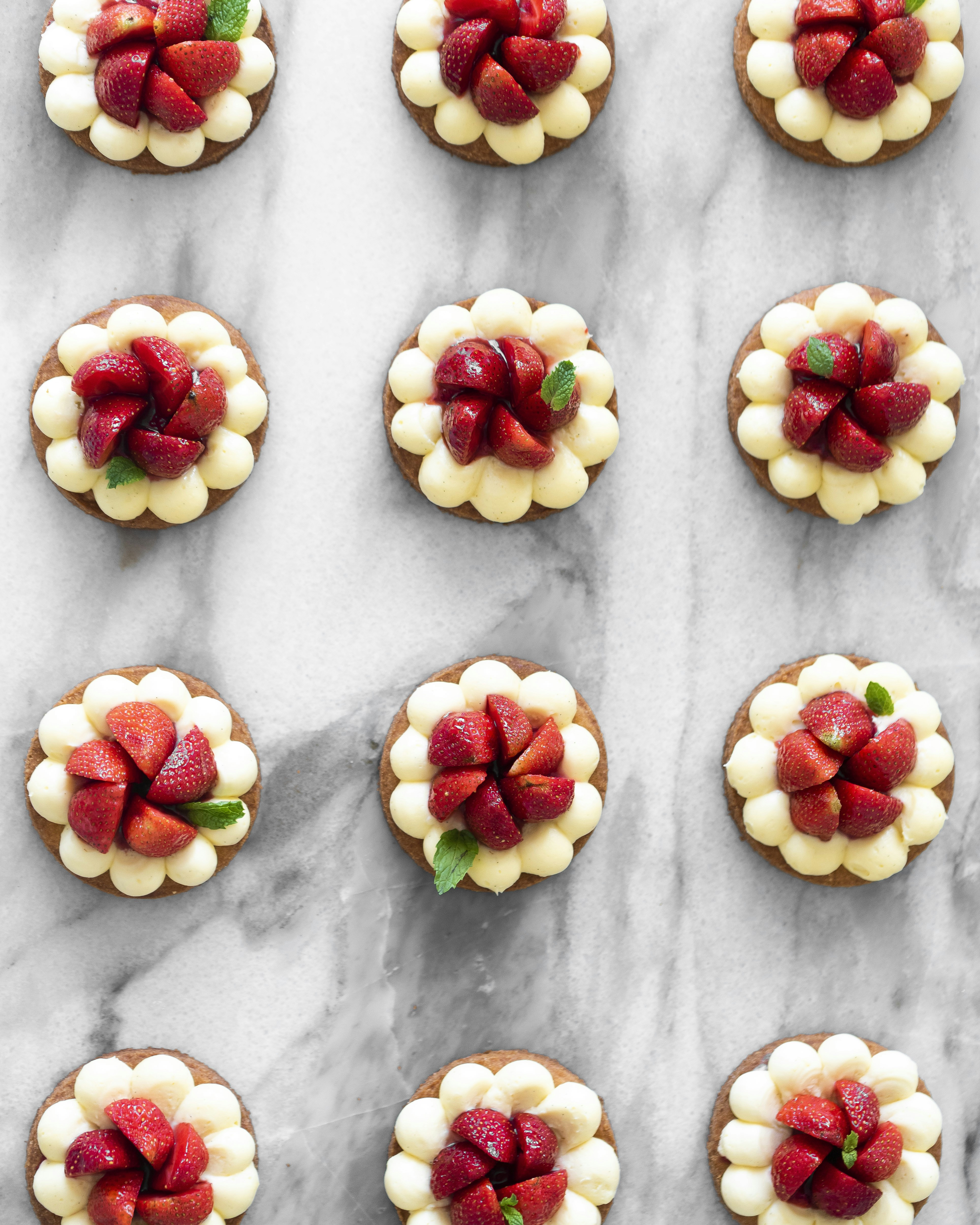 Mini tarts with strawberries and cream on marble