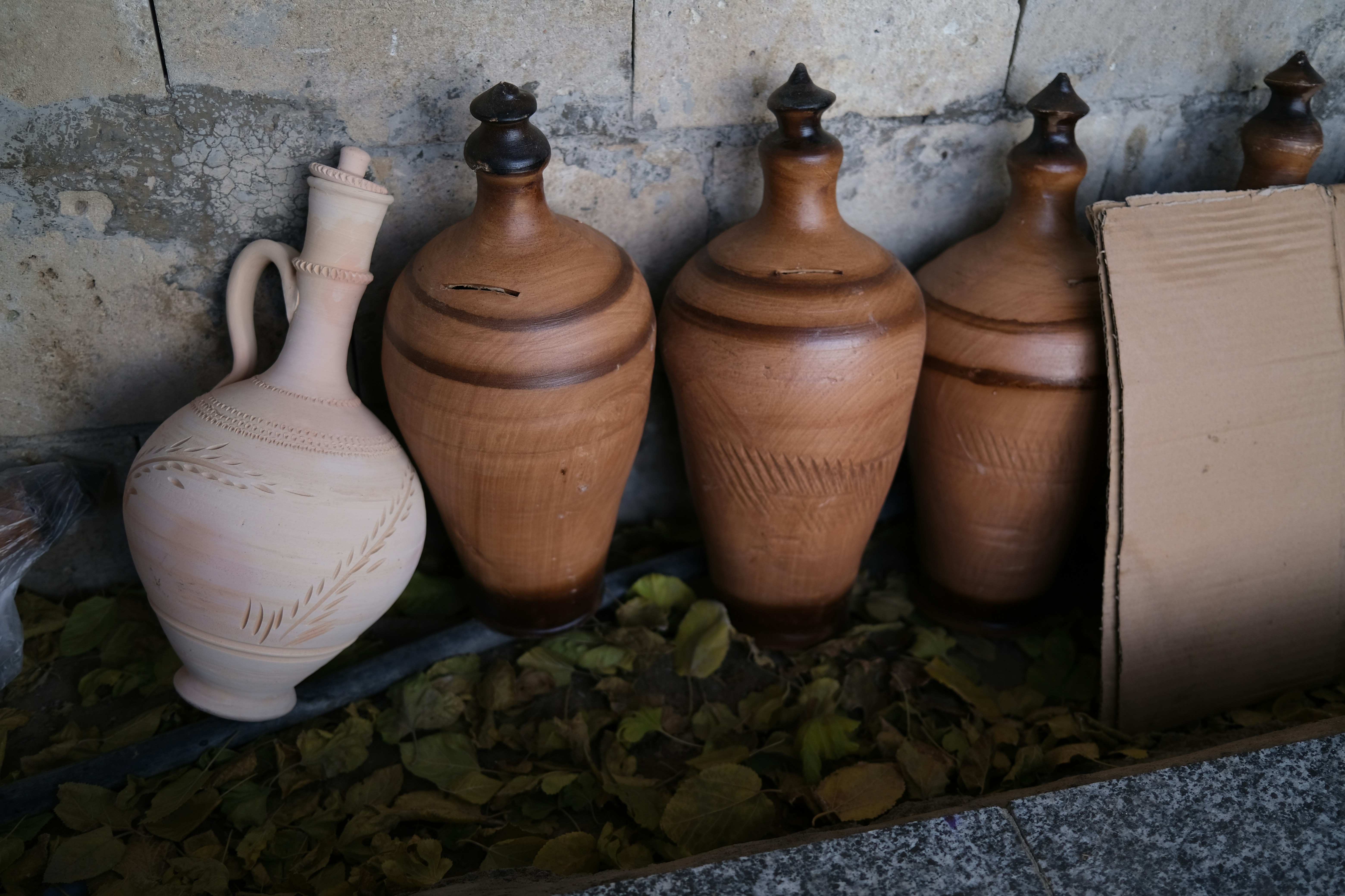 Several clay jugs and bottles on a stone surface.