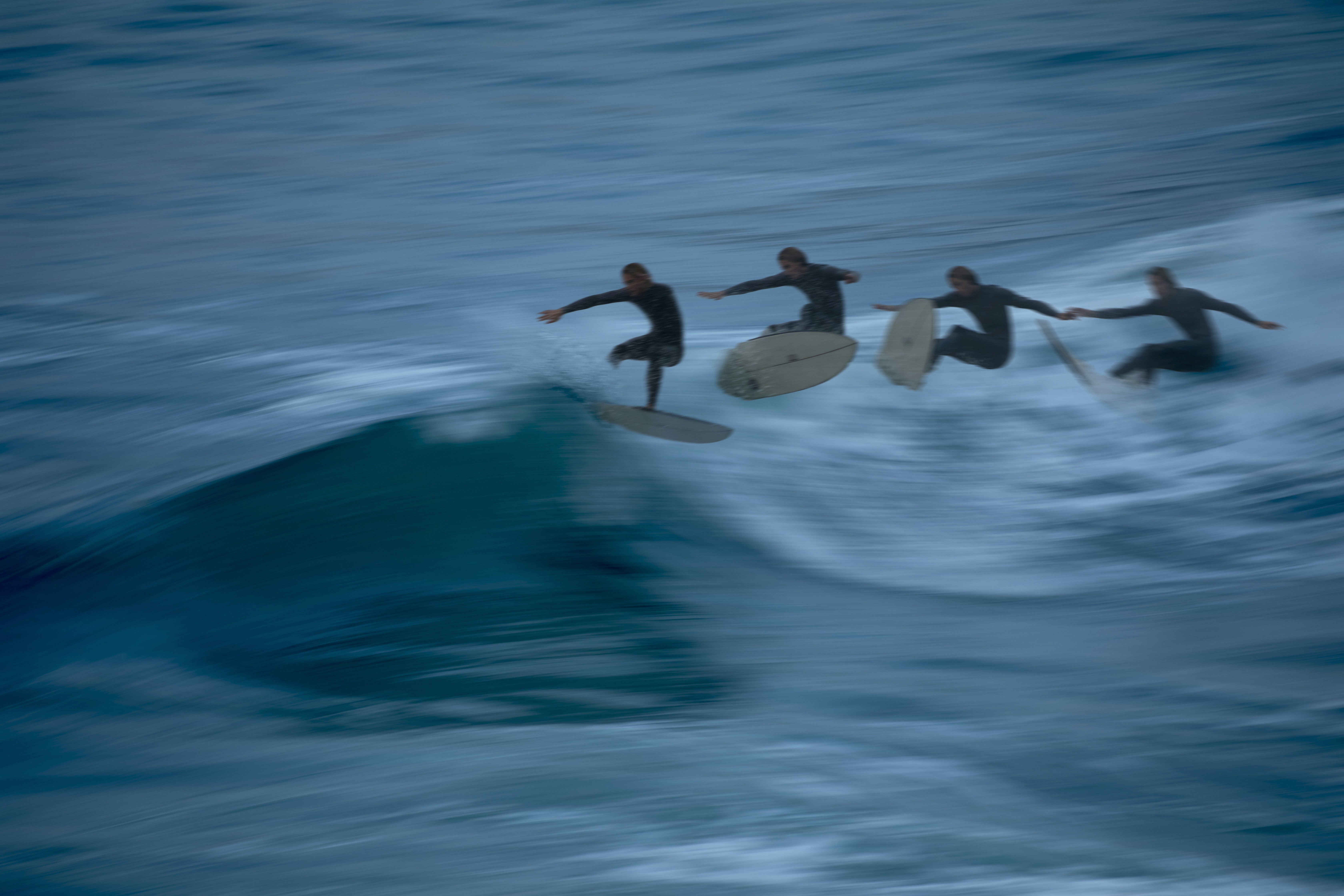 Surfers riding waves on a dark, choppy ocean
