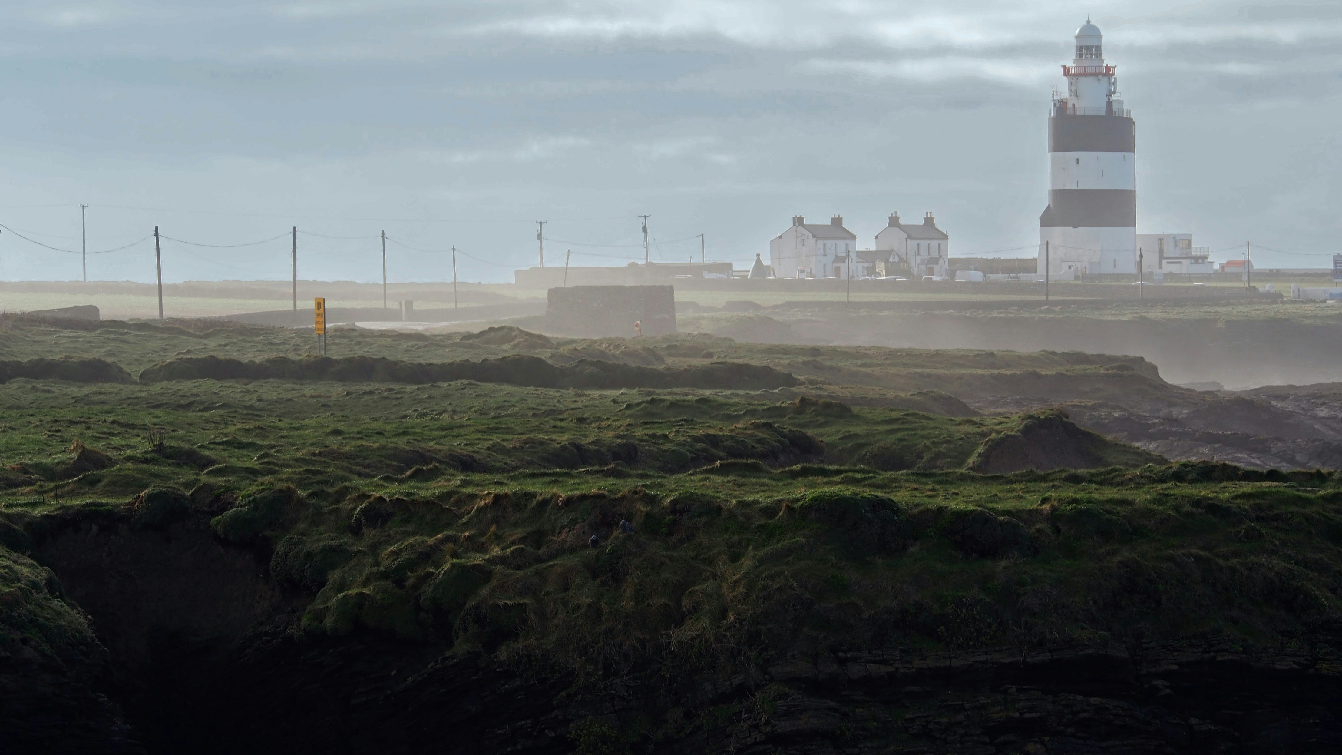 Lighthouse on a grassy cliff overlooking the sea