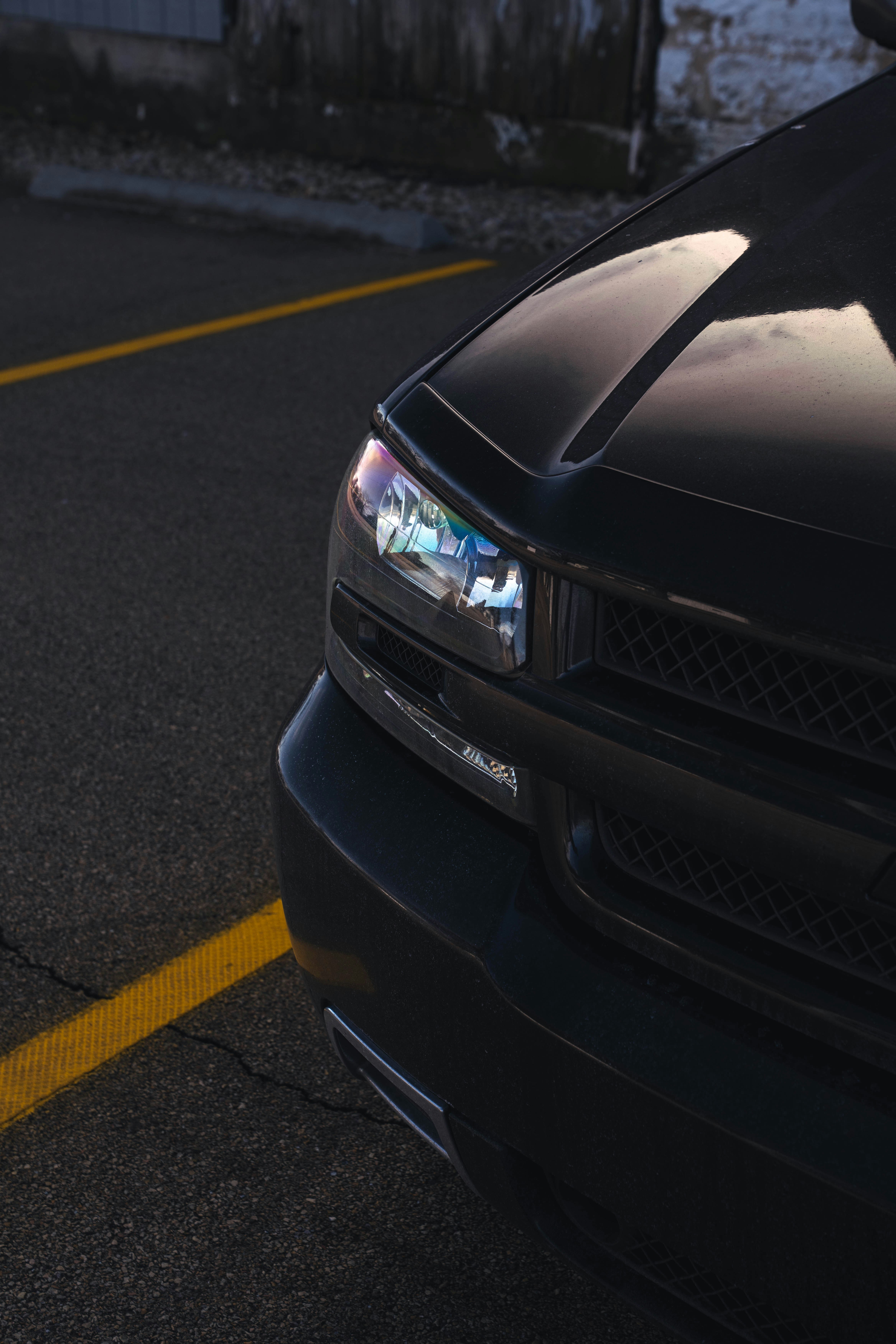 Close-up of a black car's headlight and yellow line