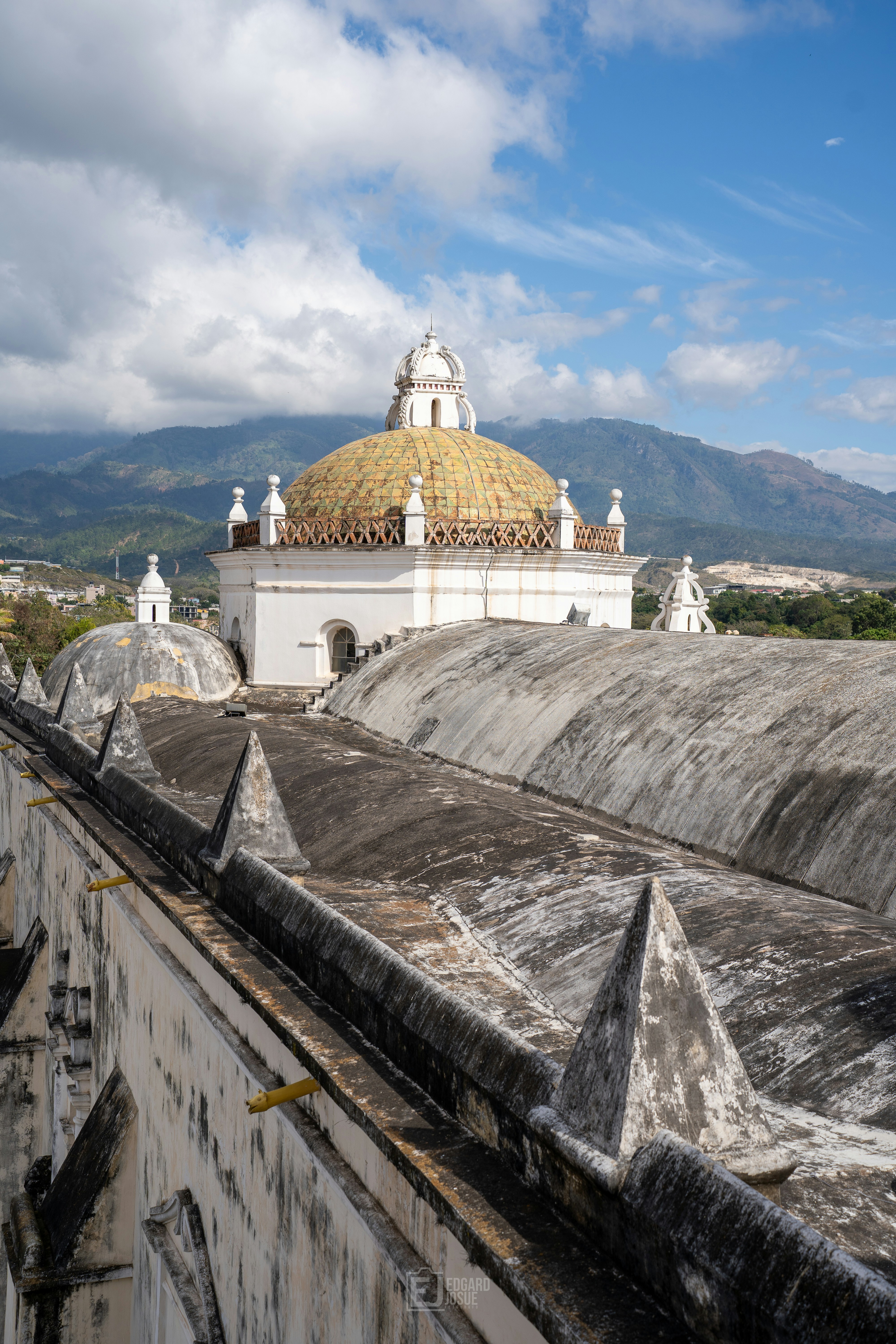 White building with a golden dome and mountains behind