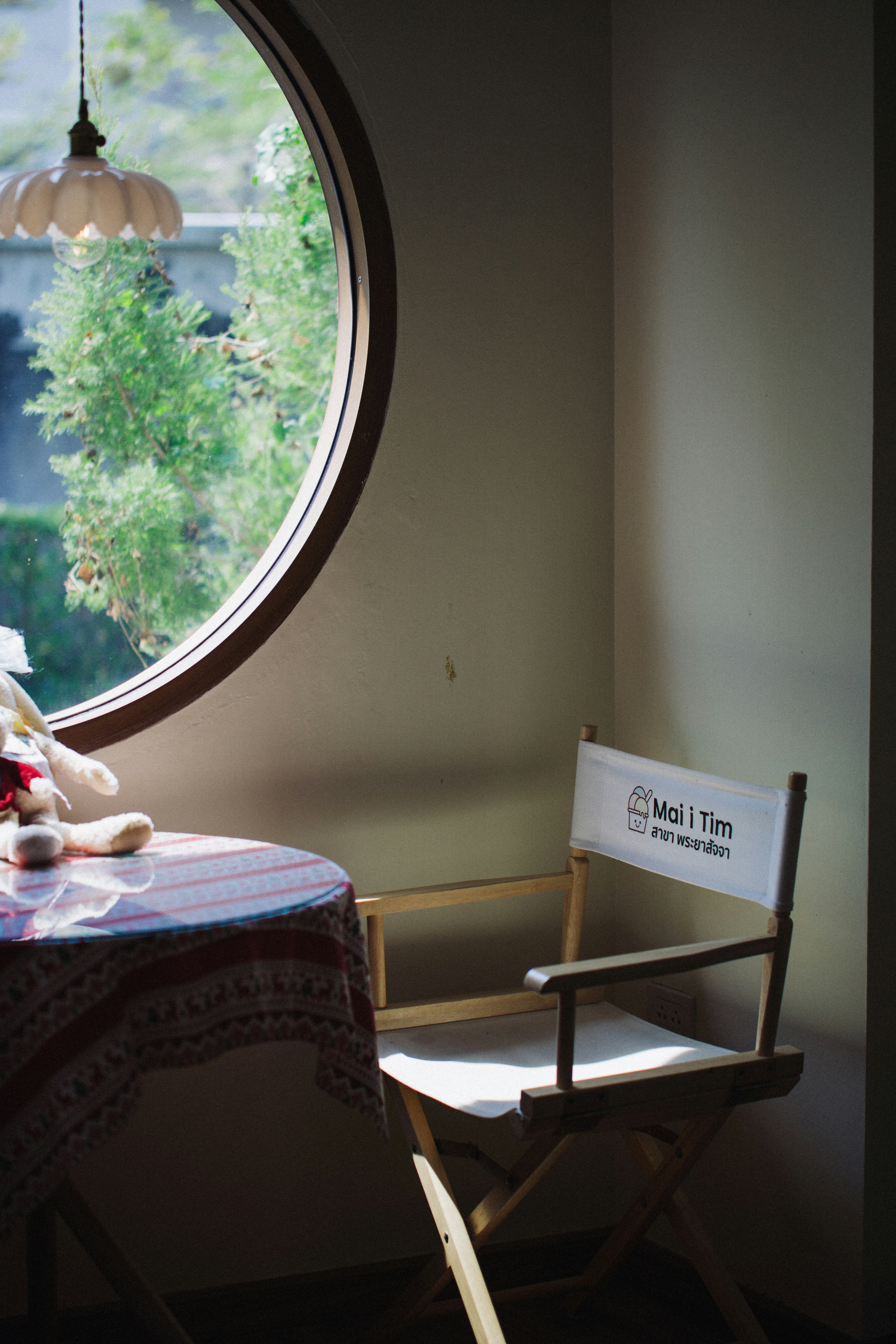 Chair by round window with stuffed animal on table