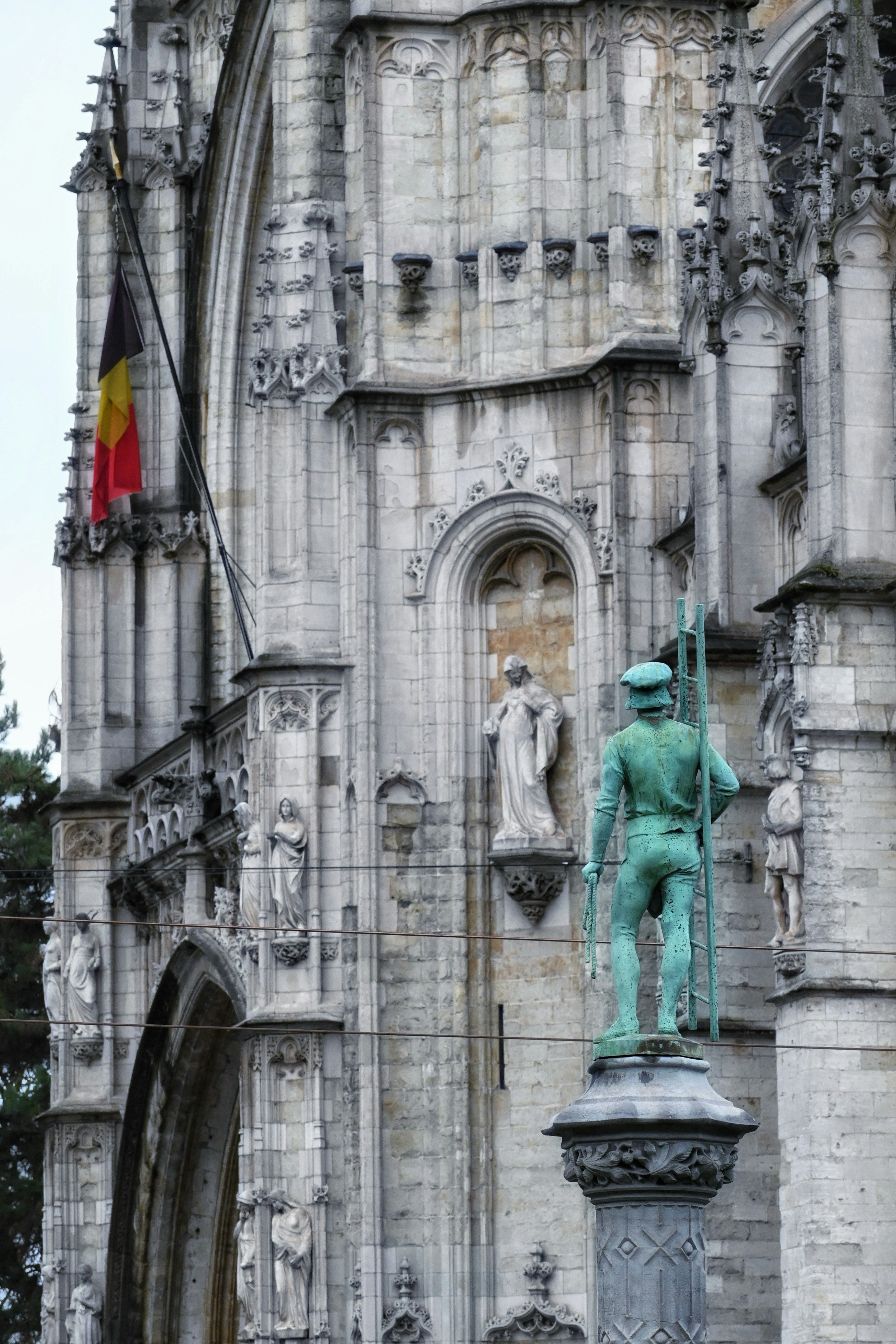 Statua davanti a una ornata architettura gotica con bandiera