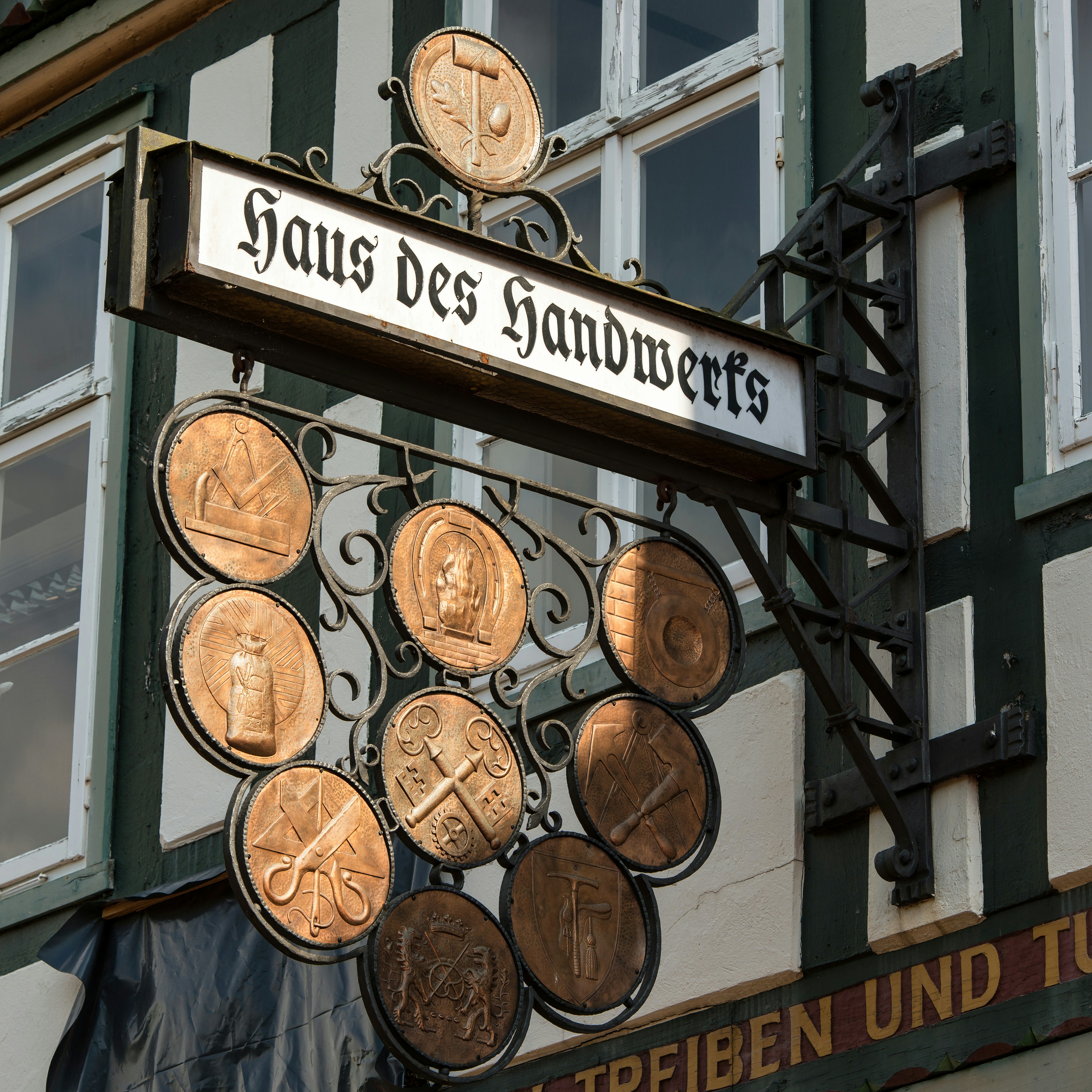 Hanging sign for haus des handwerks with decorative medallions.