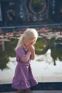 Young girl in purple dress by pond