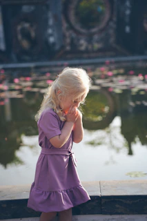 Young girl in purple dress by pond