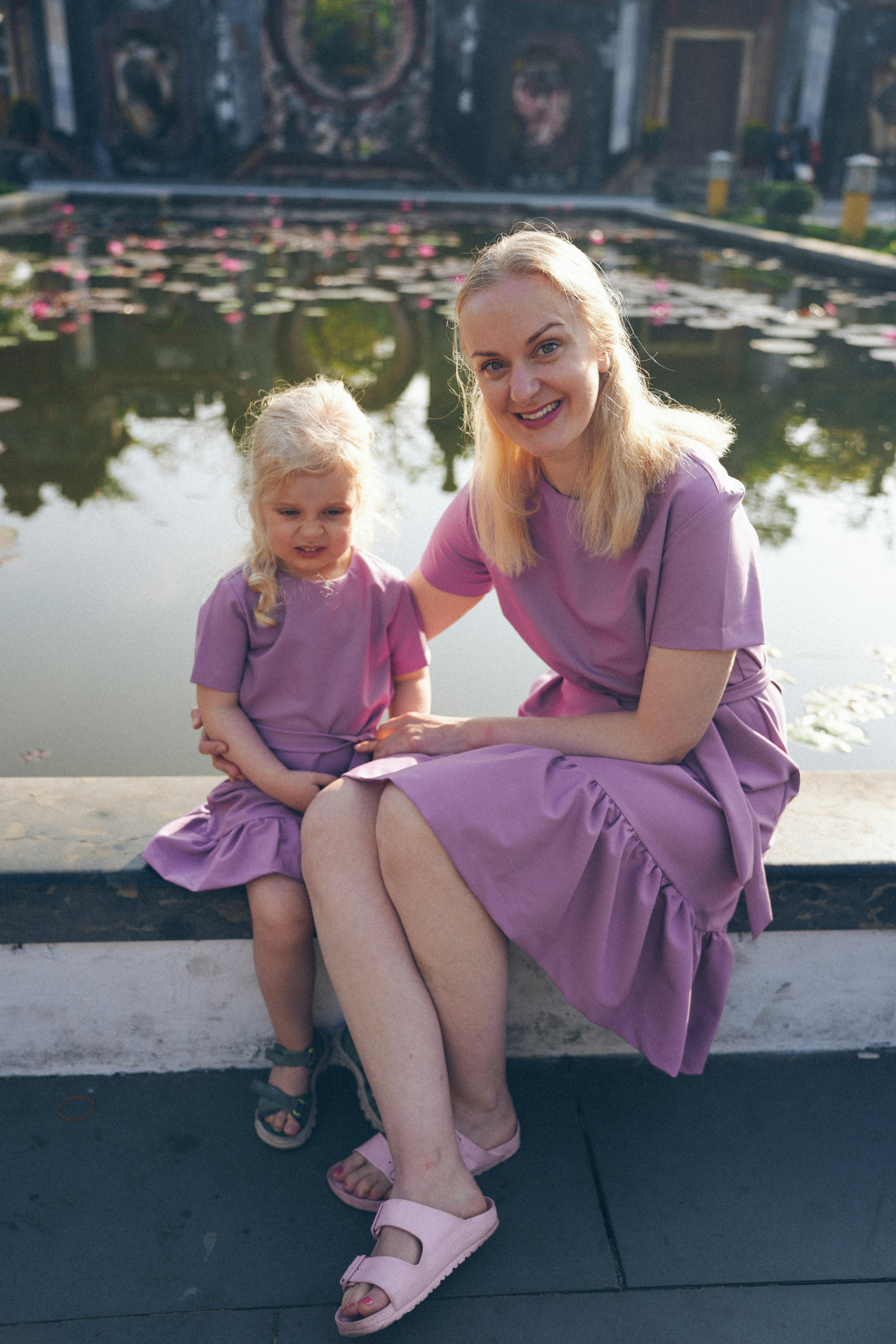 Mother and daughter in matching purple dresses by water