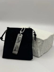 Rectangular pendant with abstract swirls on black pouch.