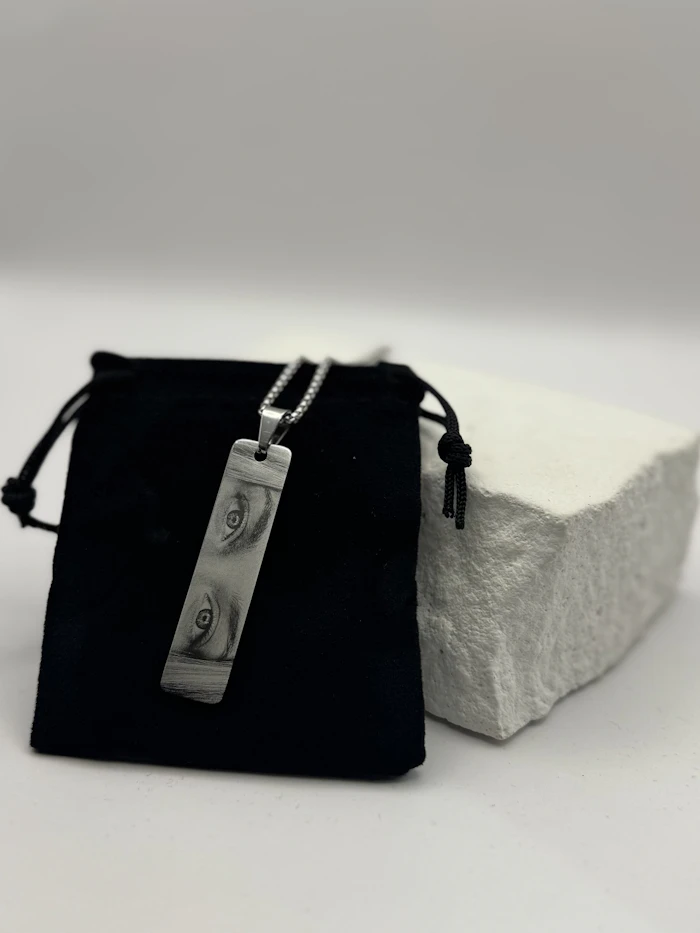 A minimal pendant resting on a pouch