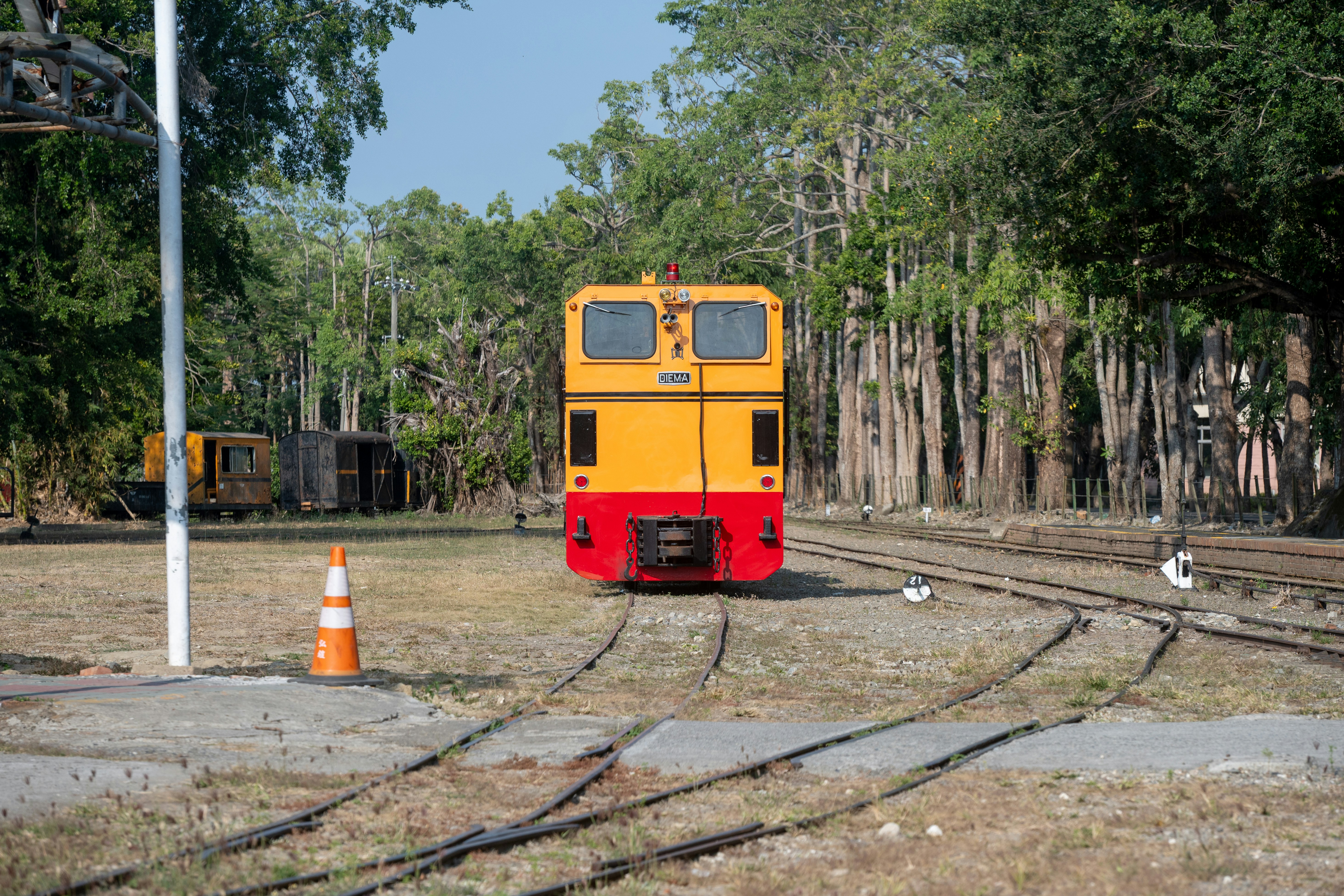 A yellow and red train sits on railroad tracks.