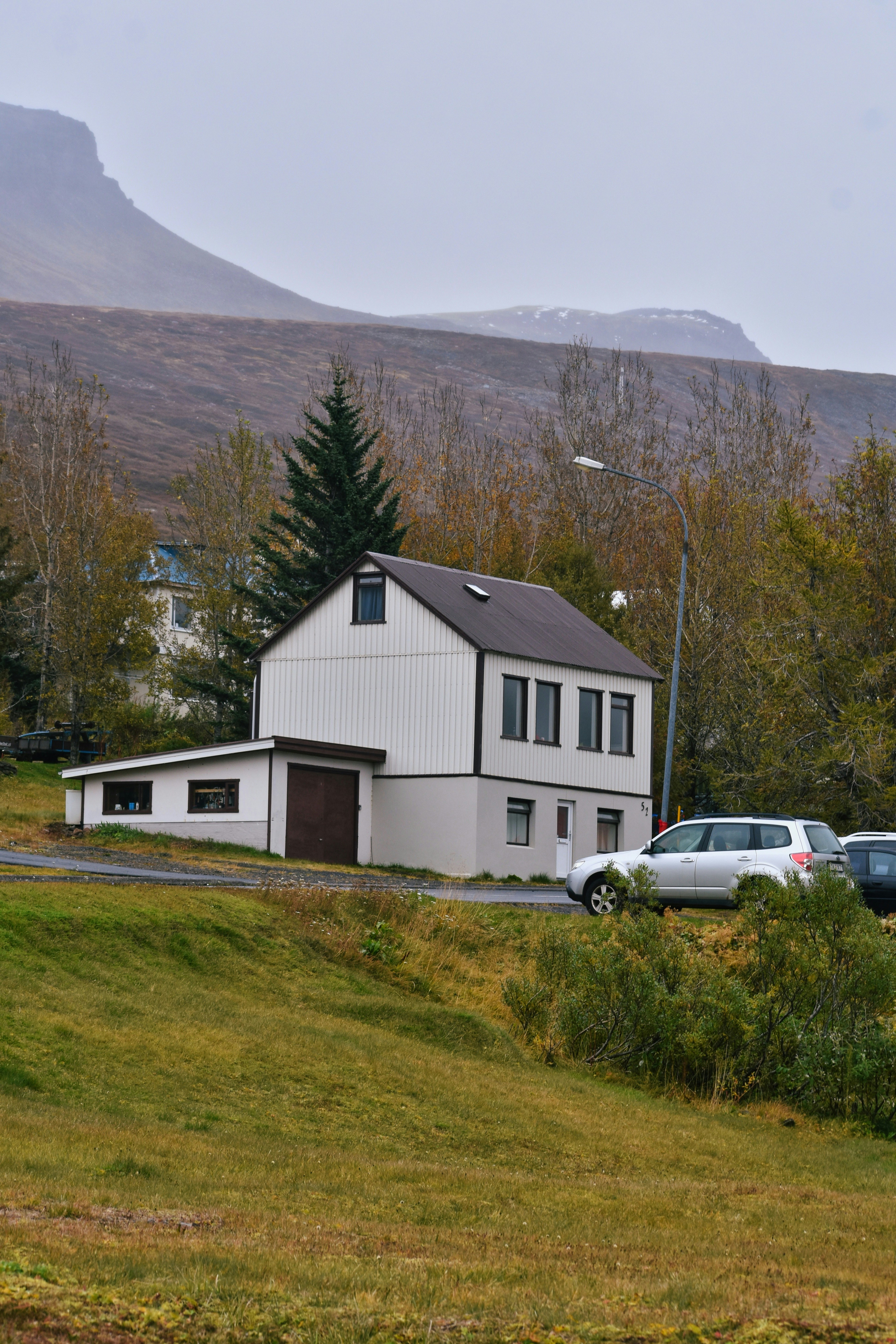 Ein weißes Haus mit einer Garage und Autos, die draußen geparkt sind.