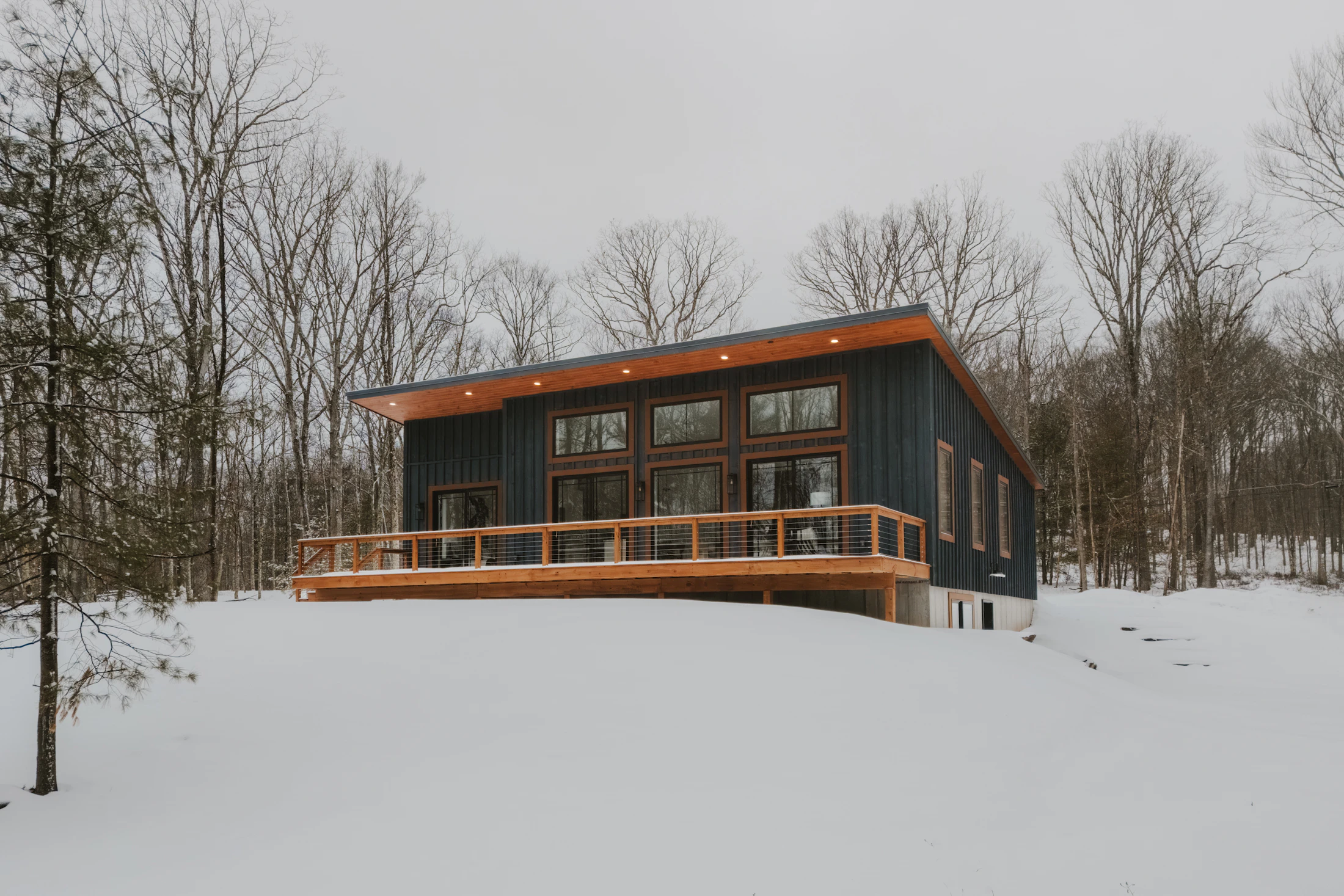 Sample inspiration photo of a modern home with a deck in snowy woods; not the property for sale