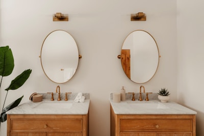 Dual wooden vanities with oval mirrors and gold fixtures