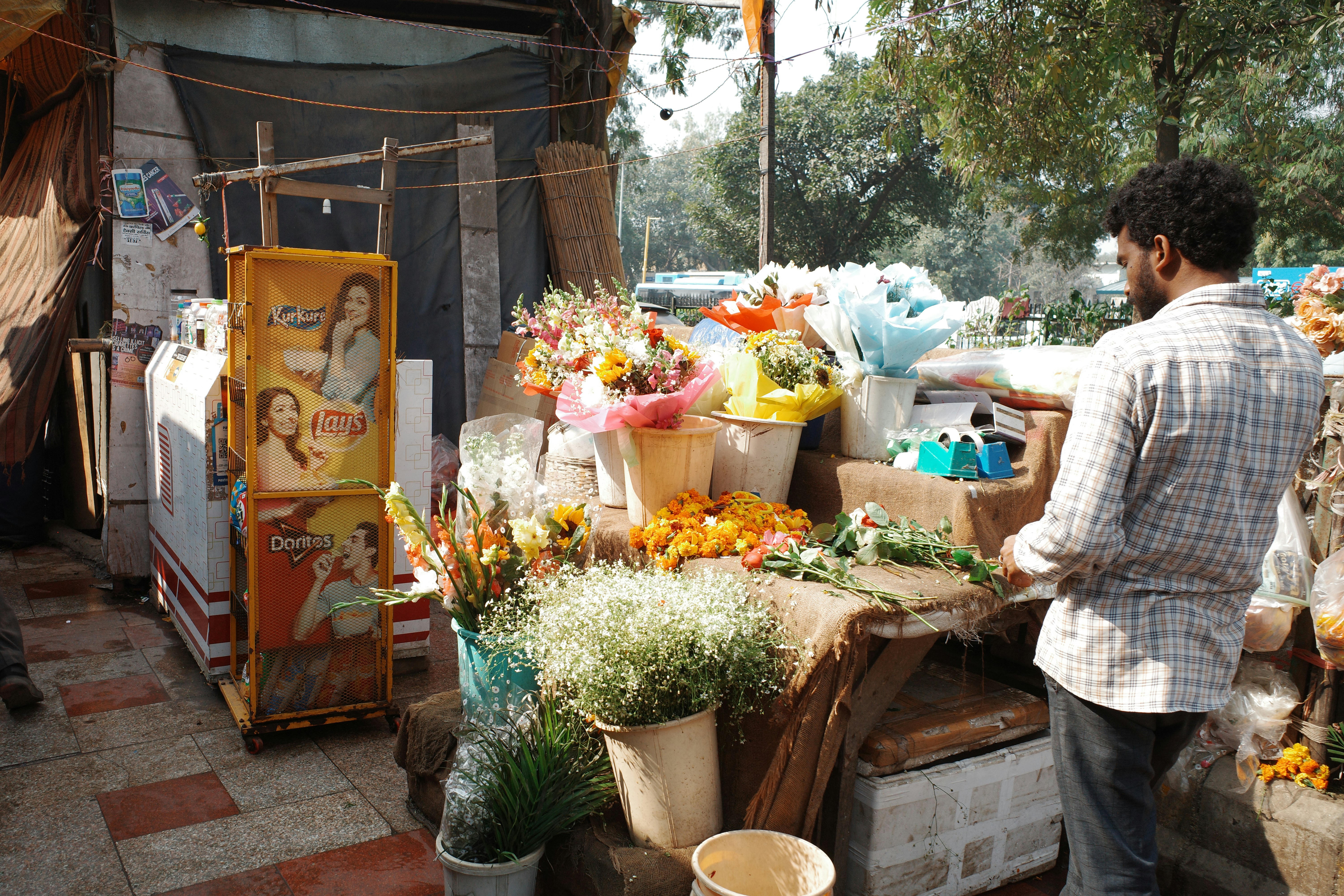 Homem está em uma barraca de flores com buquês.