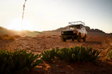 A rugged suv parked in a desert Karoo landscape at sunset.