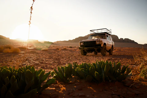 A rugged suv parked in a desert Karoo landscape at sunset.