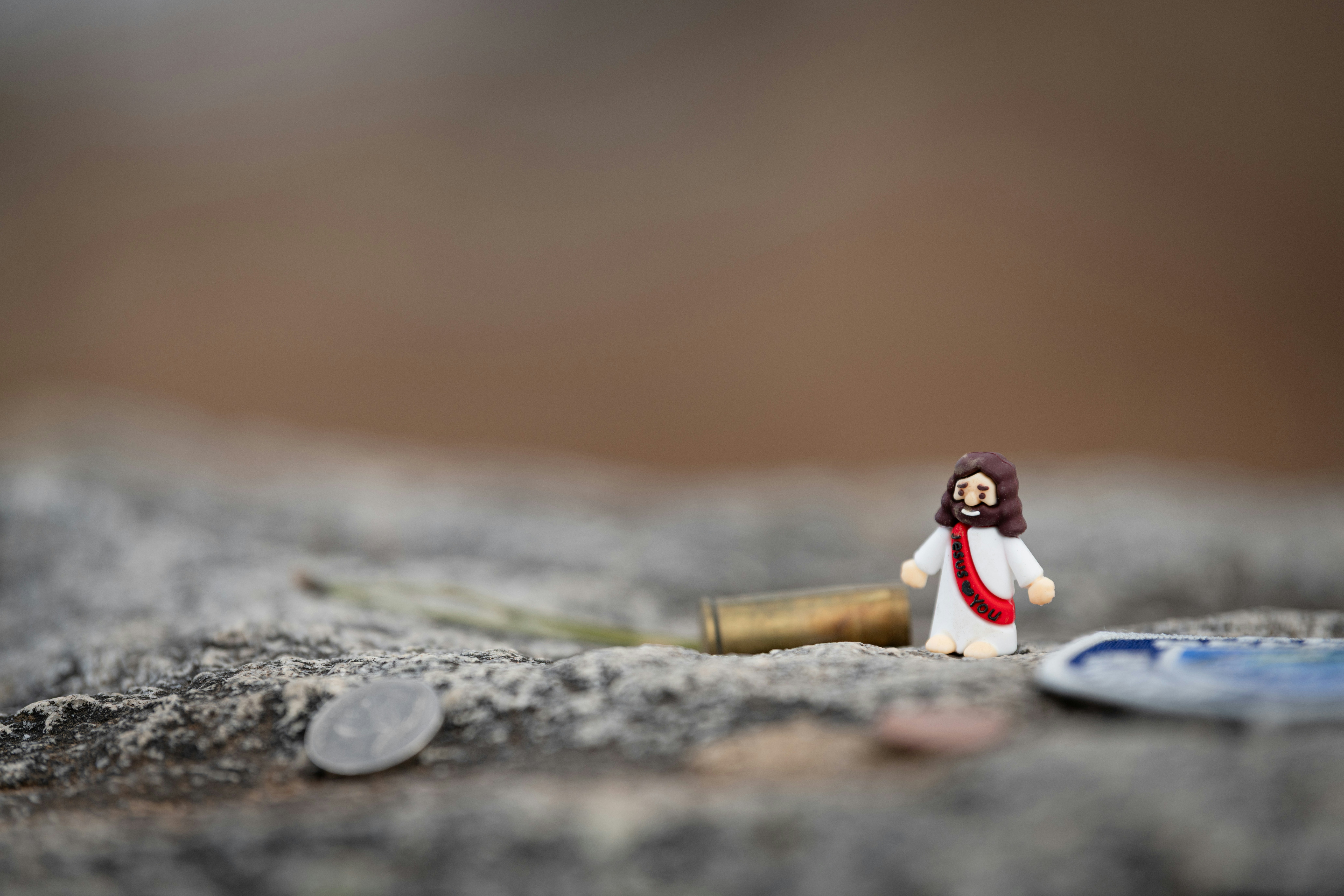 Patung Yesus miniatur dengan selubung peluru dan koin.