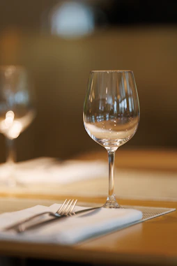 A wine glass and fork on a table setting