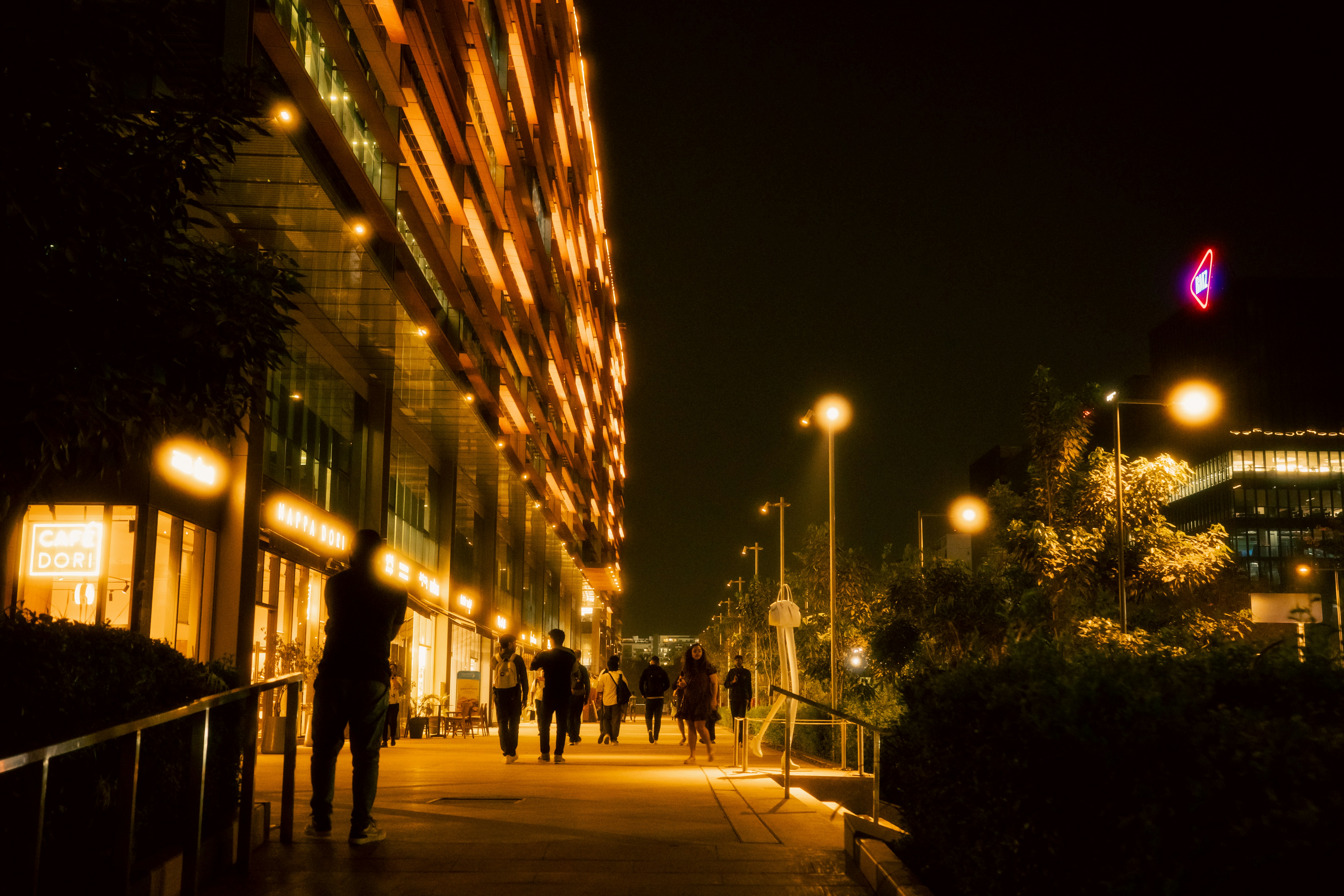 Persone che camminano su un sentiero di notte vicino a edifici illuminati.