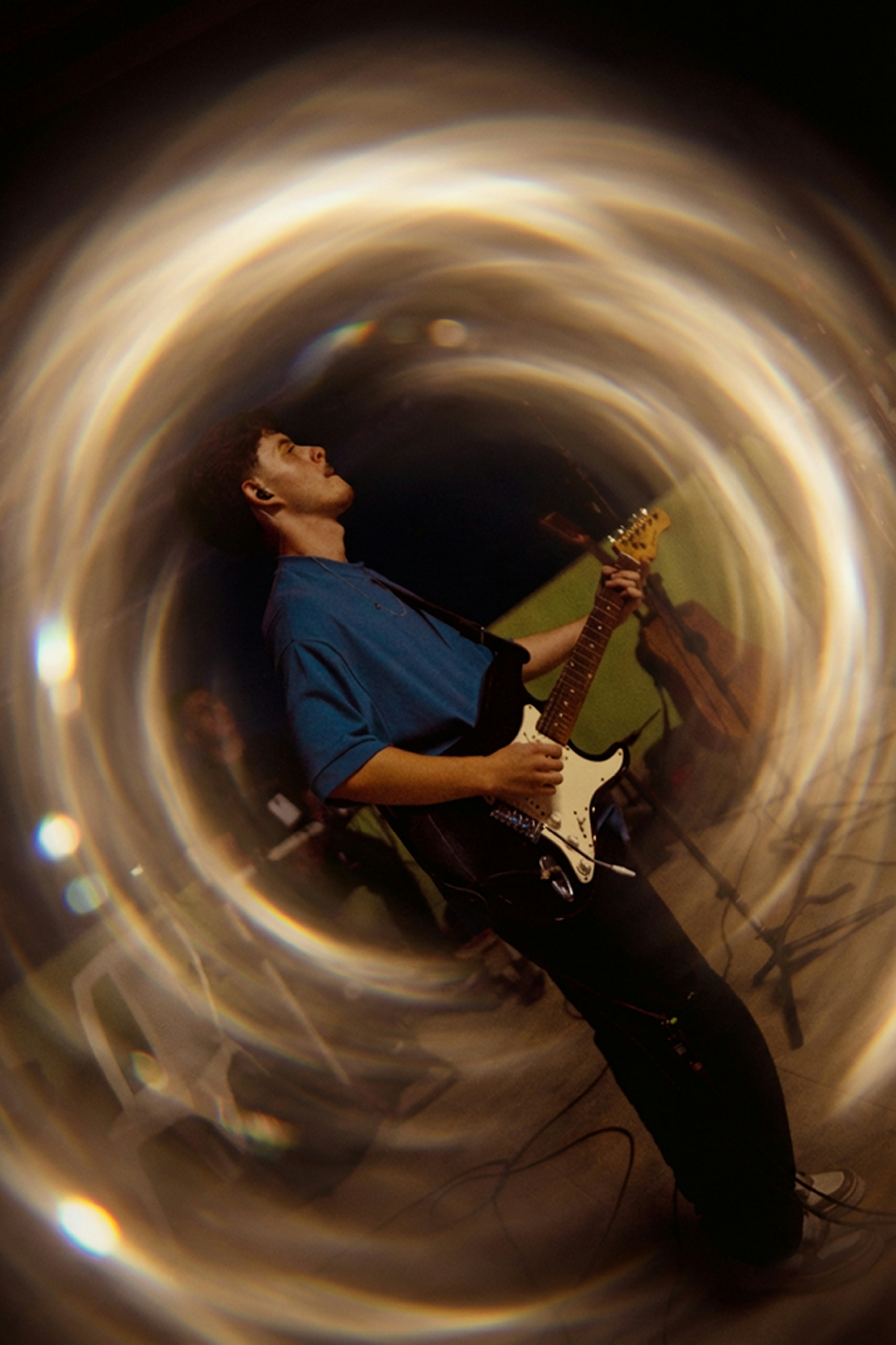 Man playing electric guitar with swirling light effects