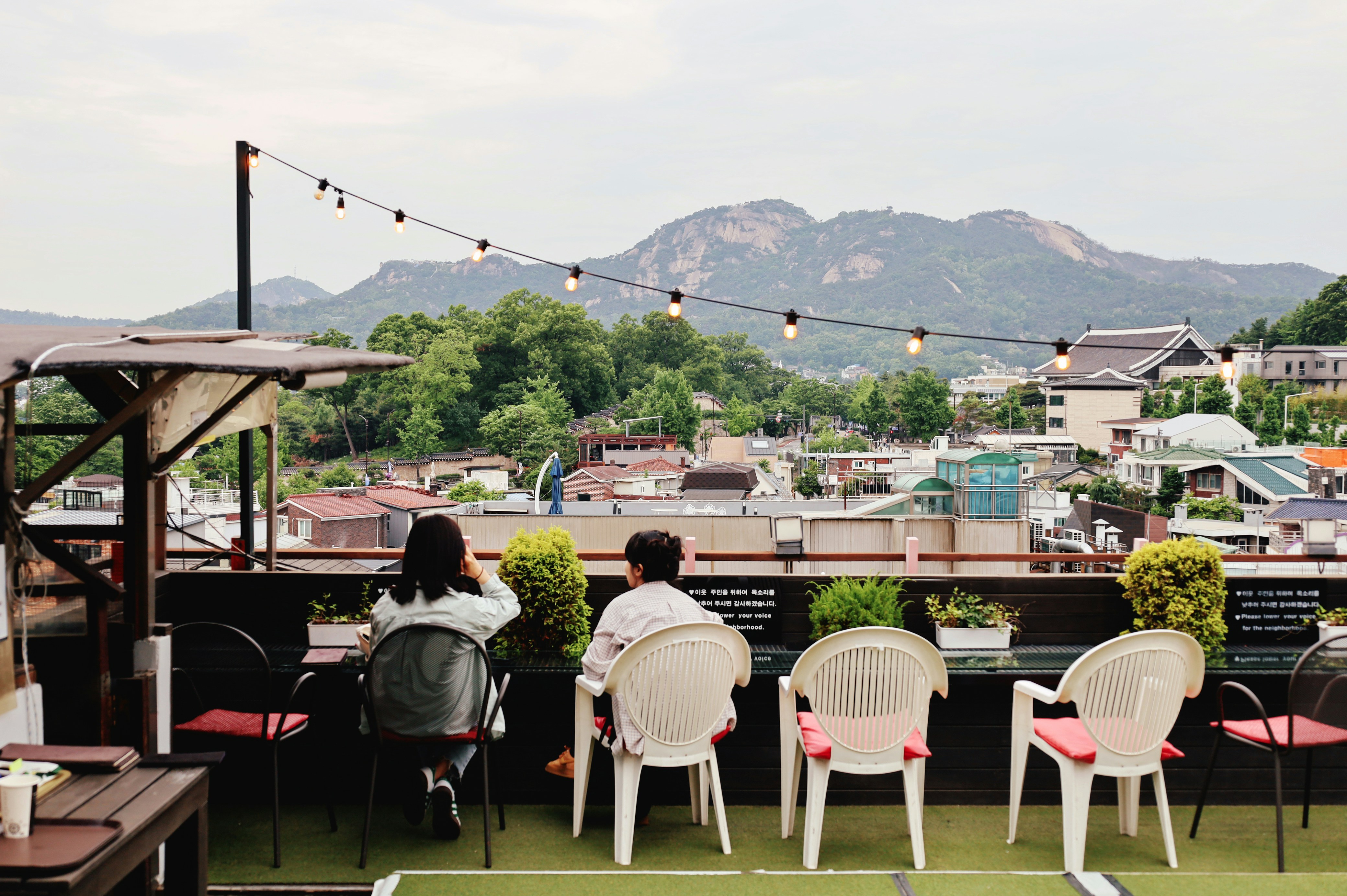 A crowded rooftop lounge overlooking a city skyline at sunset - fun bars