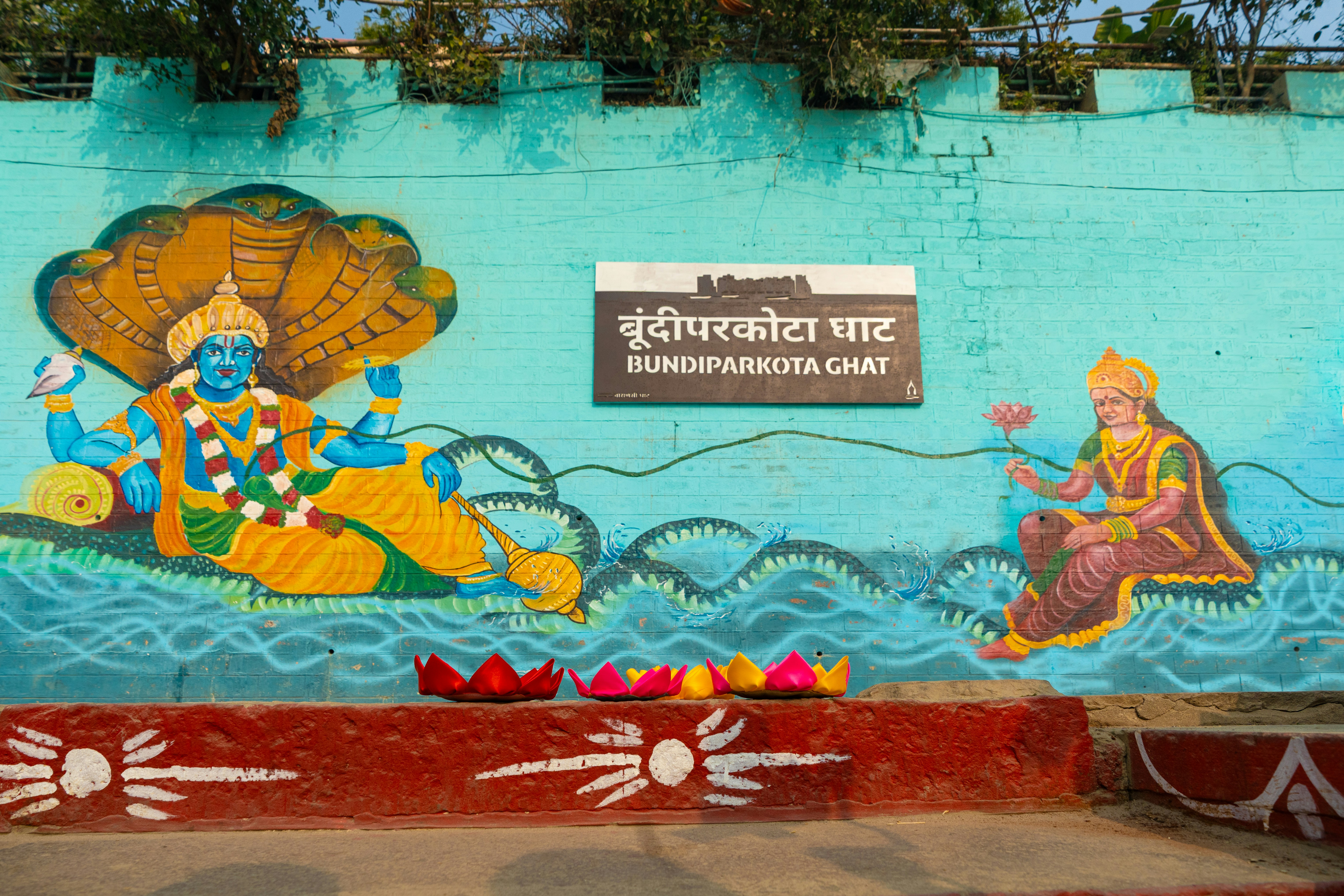Hindu deities painted on a turquoise wall with lotus flowers
