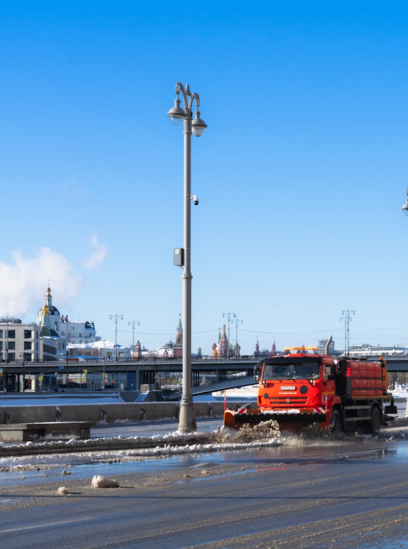 Snowplow truck clearing a paved road with snow moving off the blade