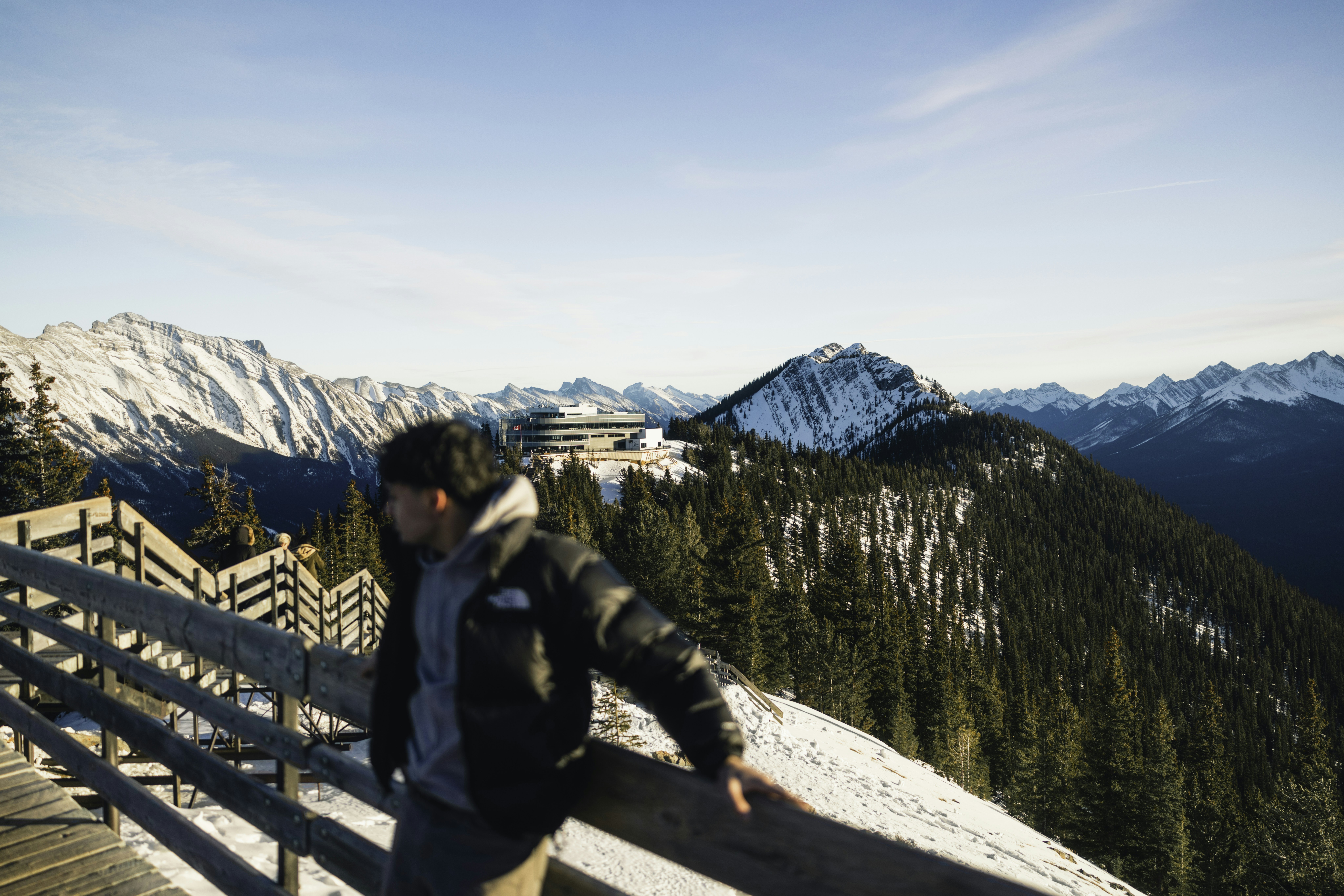 Man looking at snowy mountain landscape from wooden walkway