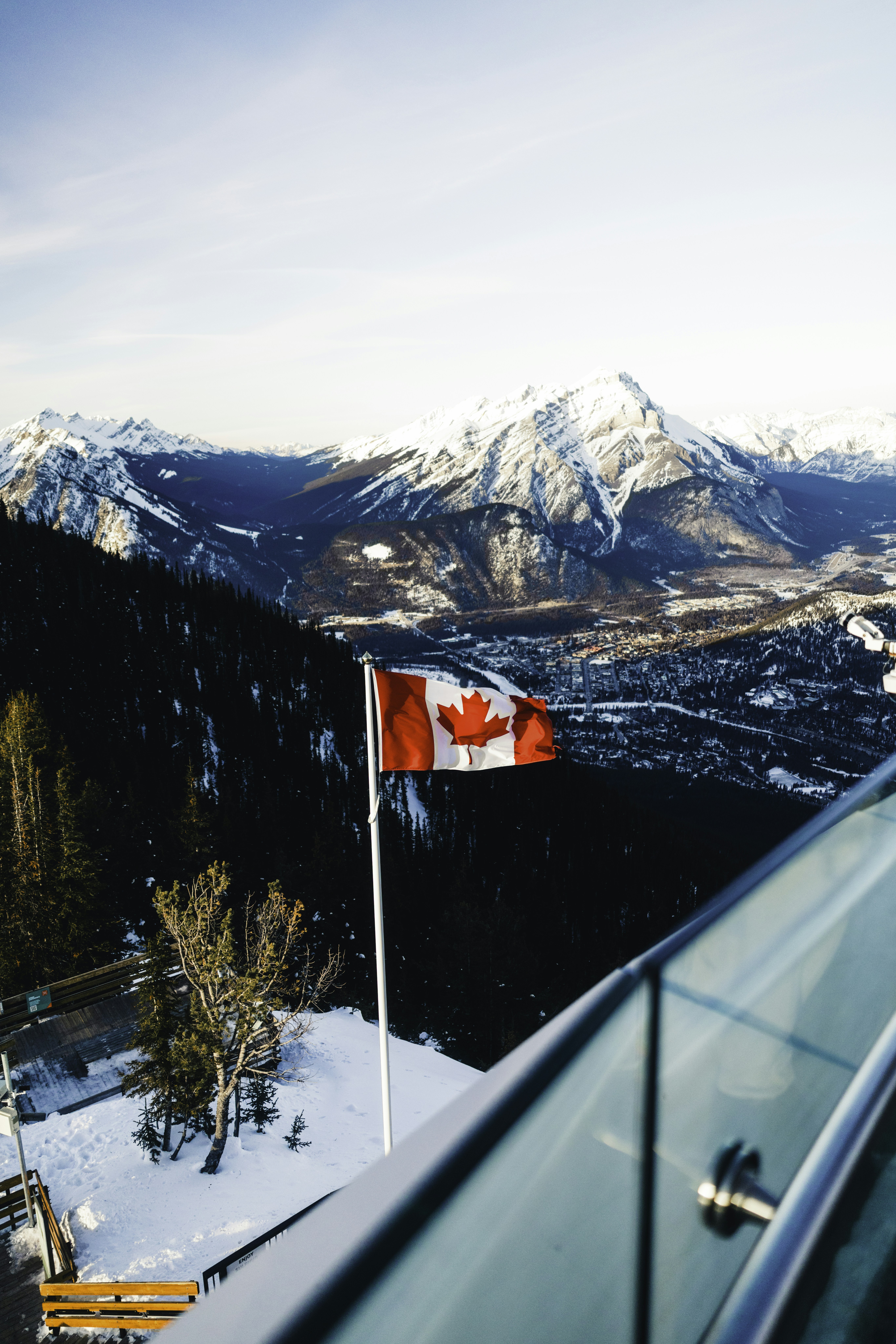 Canadian flag flies over snowy mountain landscape.