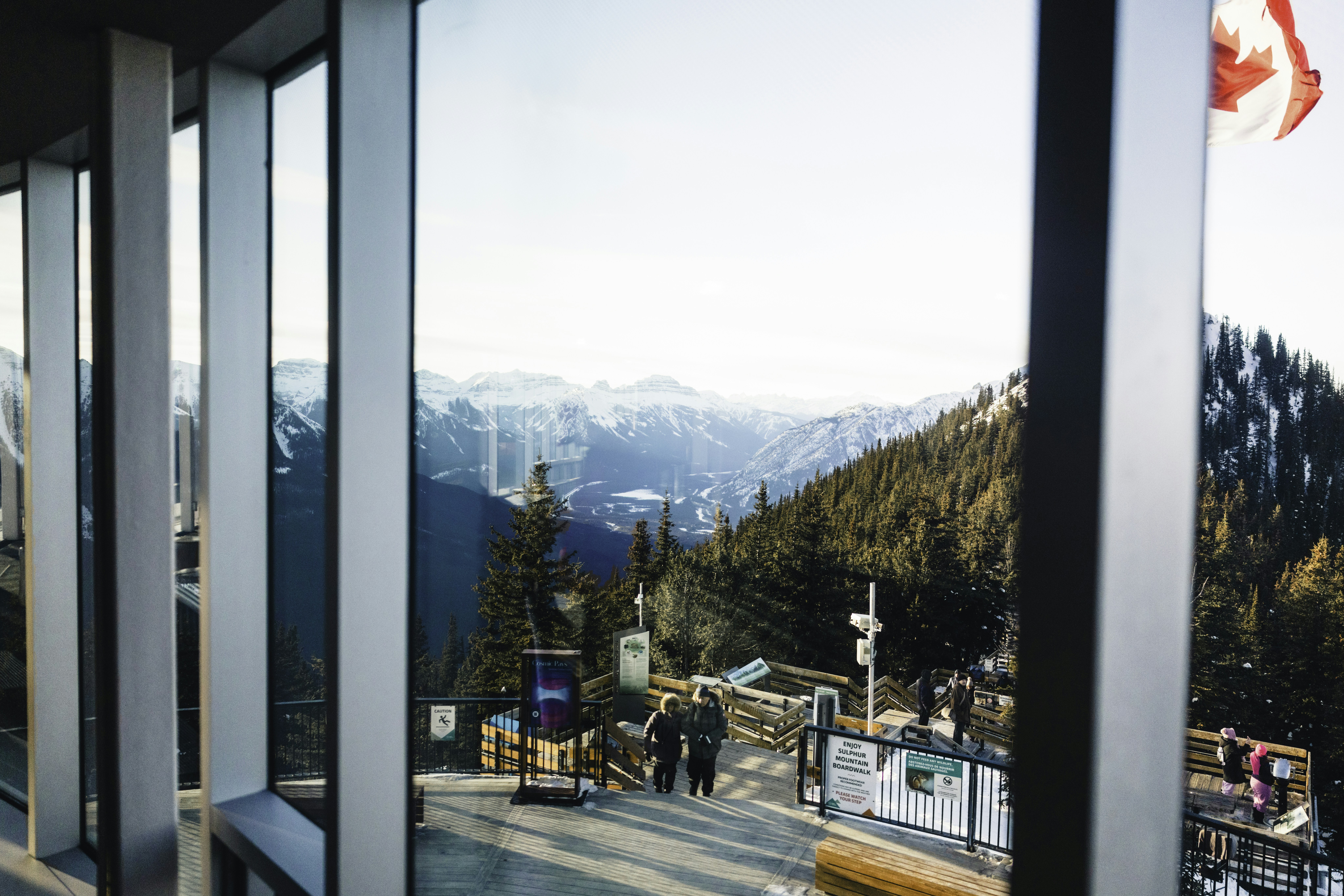 Mountain landscape viewed through large windows with canadian flag.