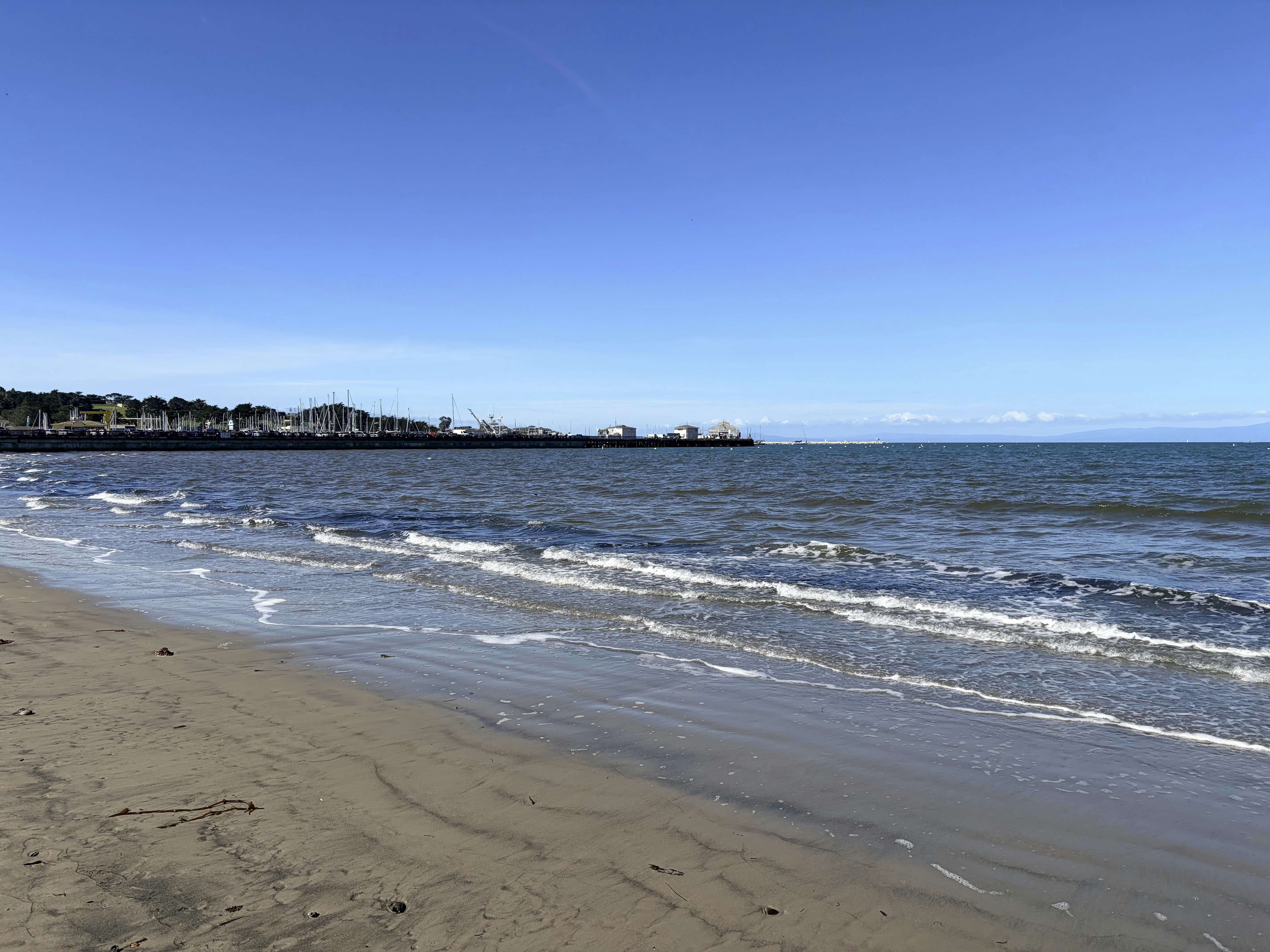 Sandy beach with gentle waves under a clear blue sky