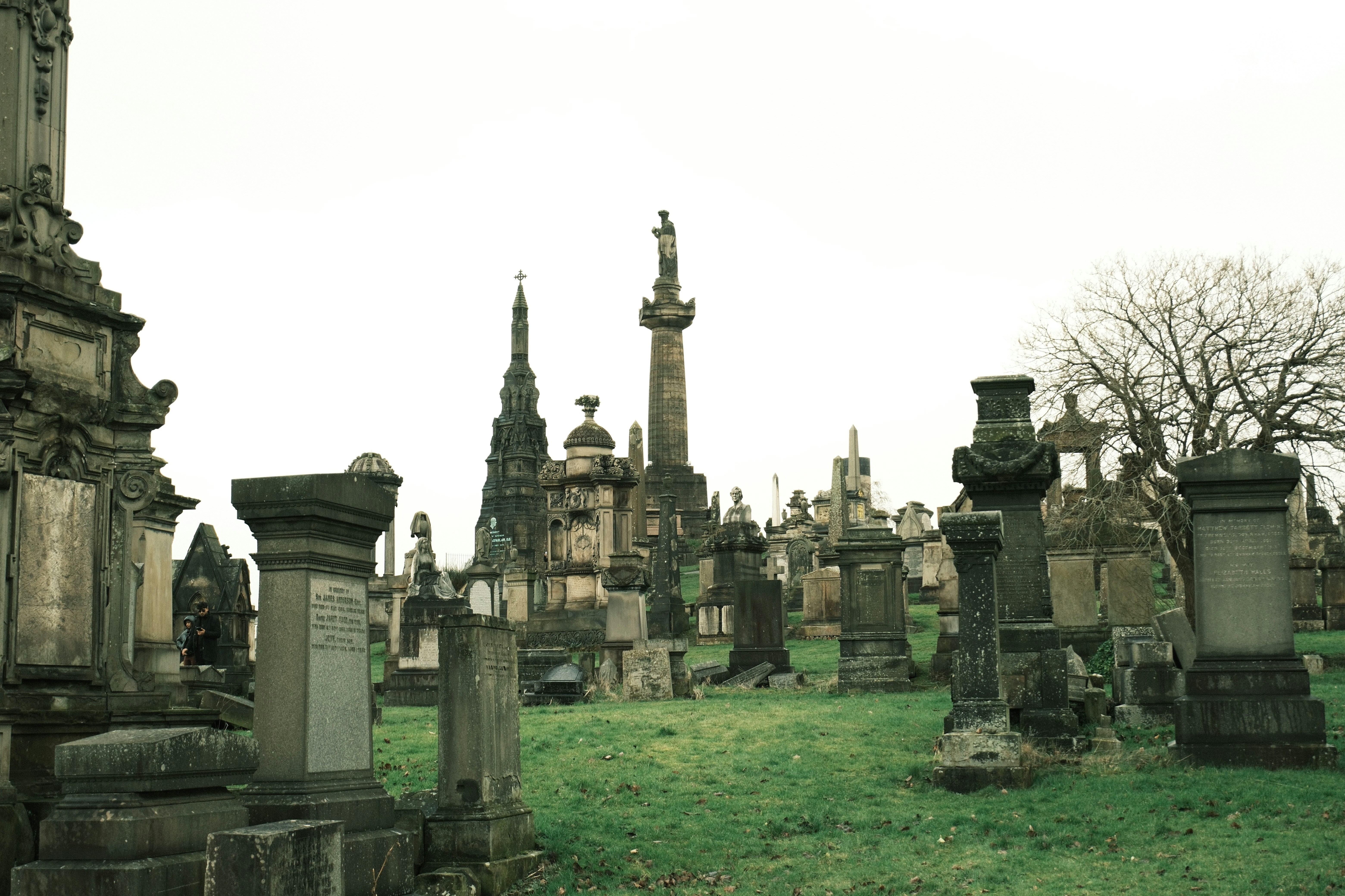 Ein alter Friedhof mit aufwendigen Steindenkmälern und Bäumen.