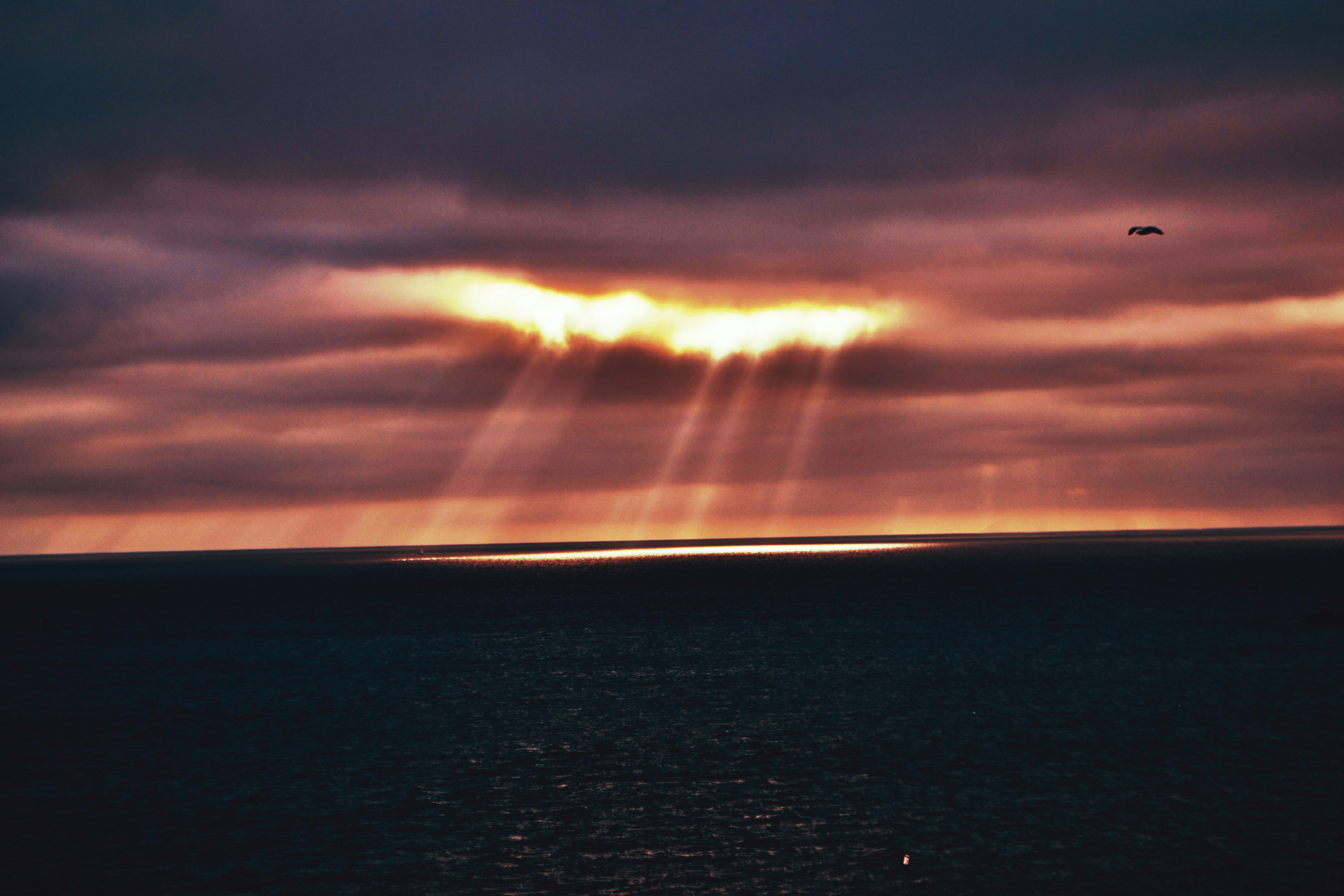 Sunbeams breaking through dramatic clouds over ocean.