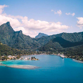Tropical bay with lush green mountains and clear blue water.