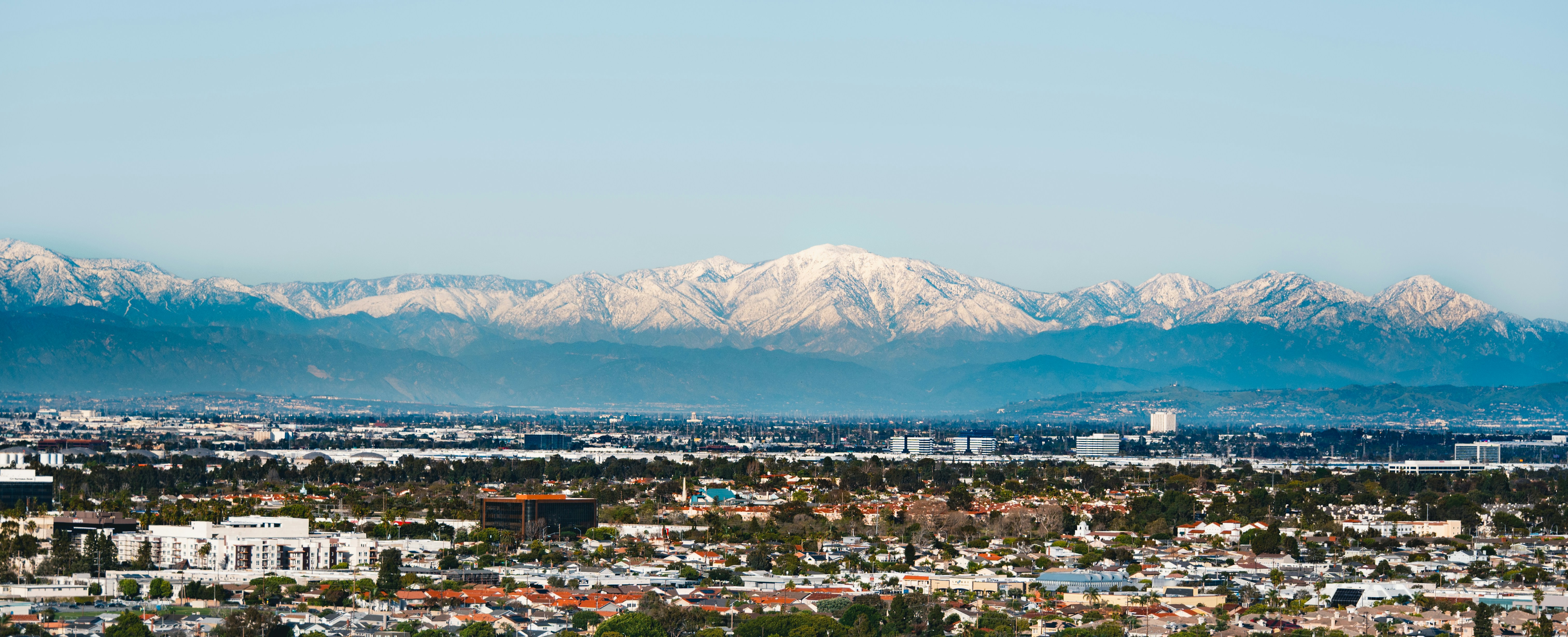 Montanhas cobertas de neve se erguem sobre uma vasta paisagem urbana.