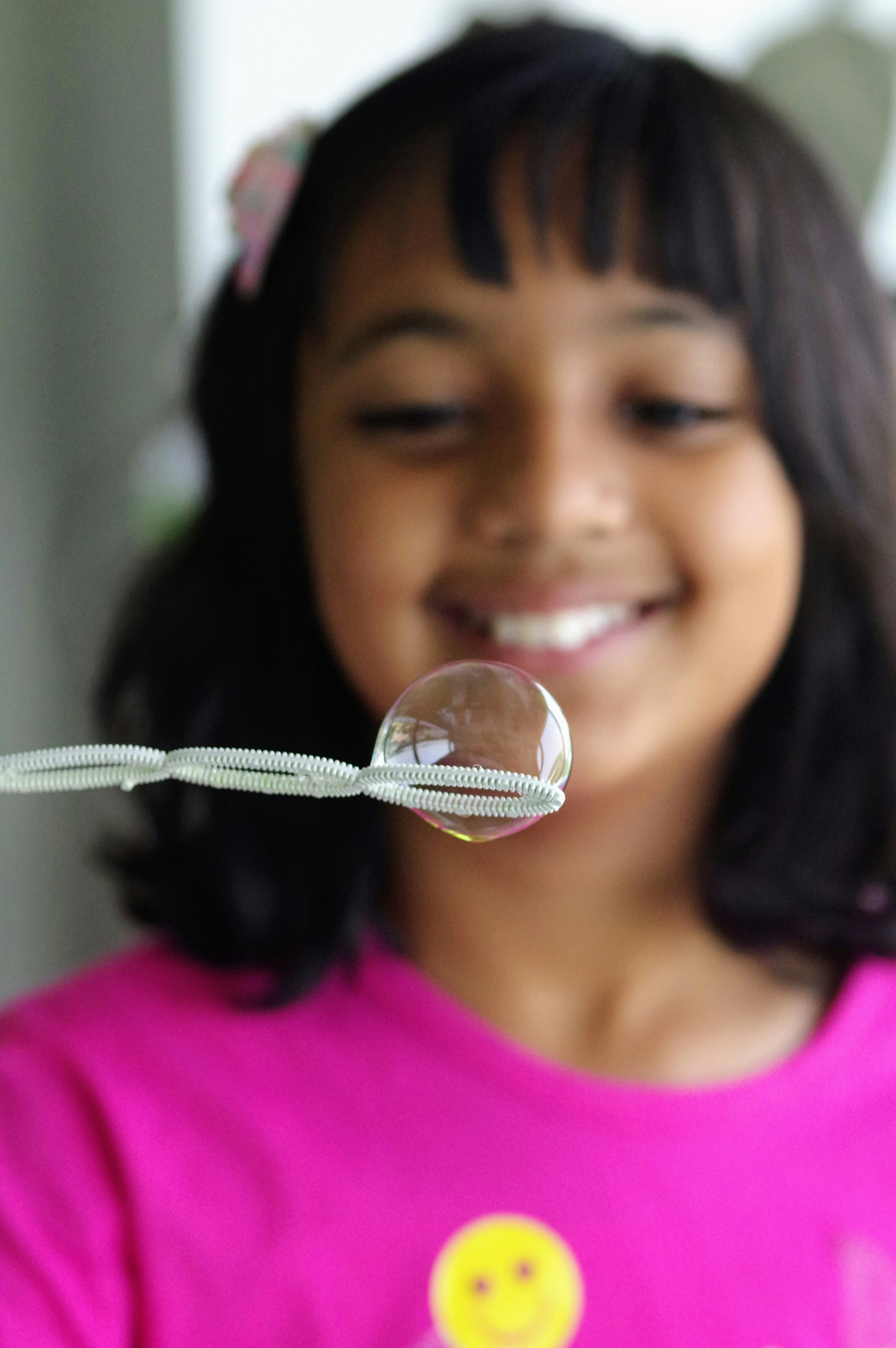 Ein junges Mädchen in einem rosa Hemd bläst eine Blase.