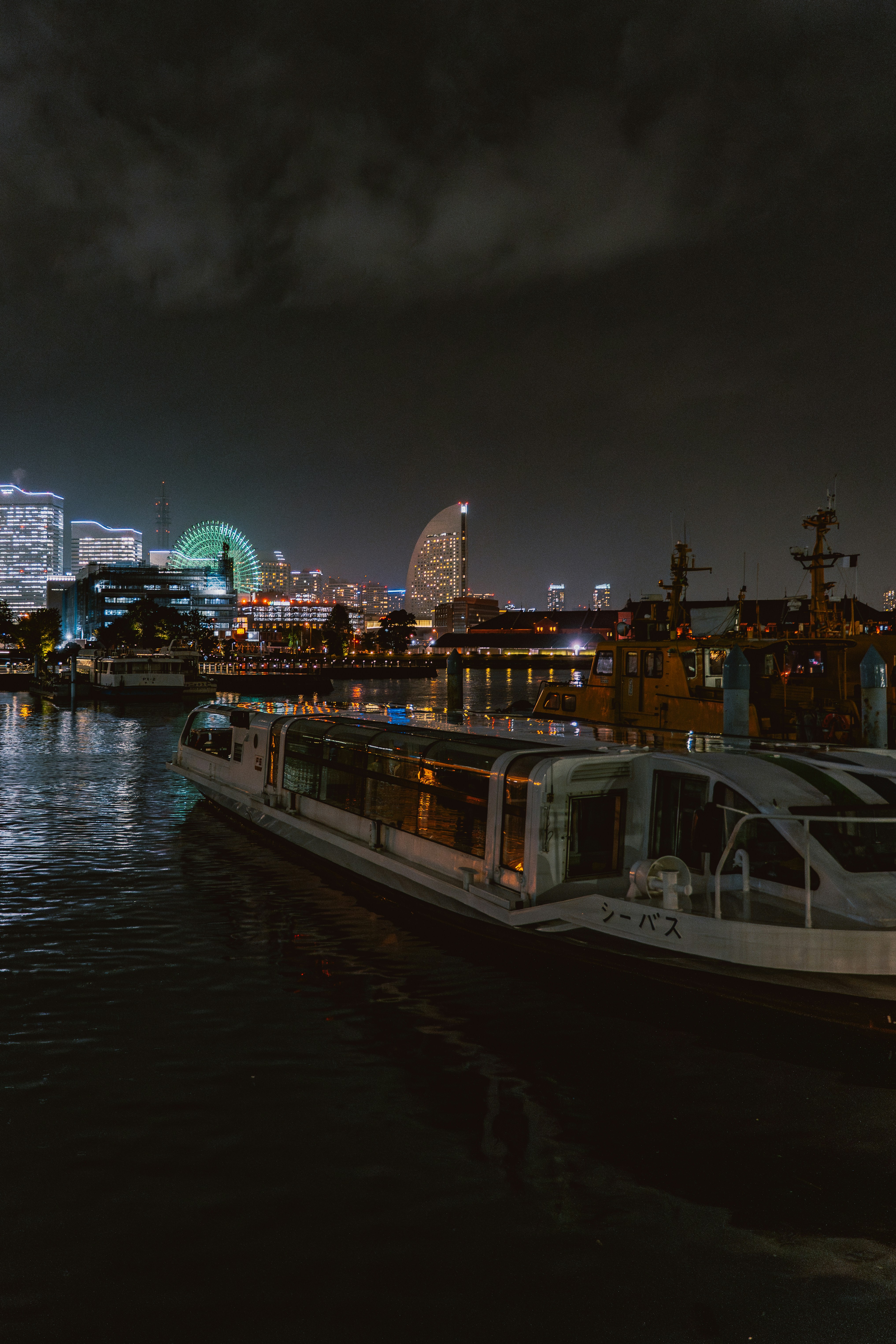 A boat on the water at night with city lights.