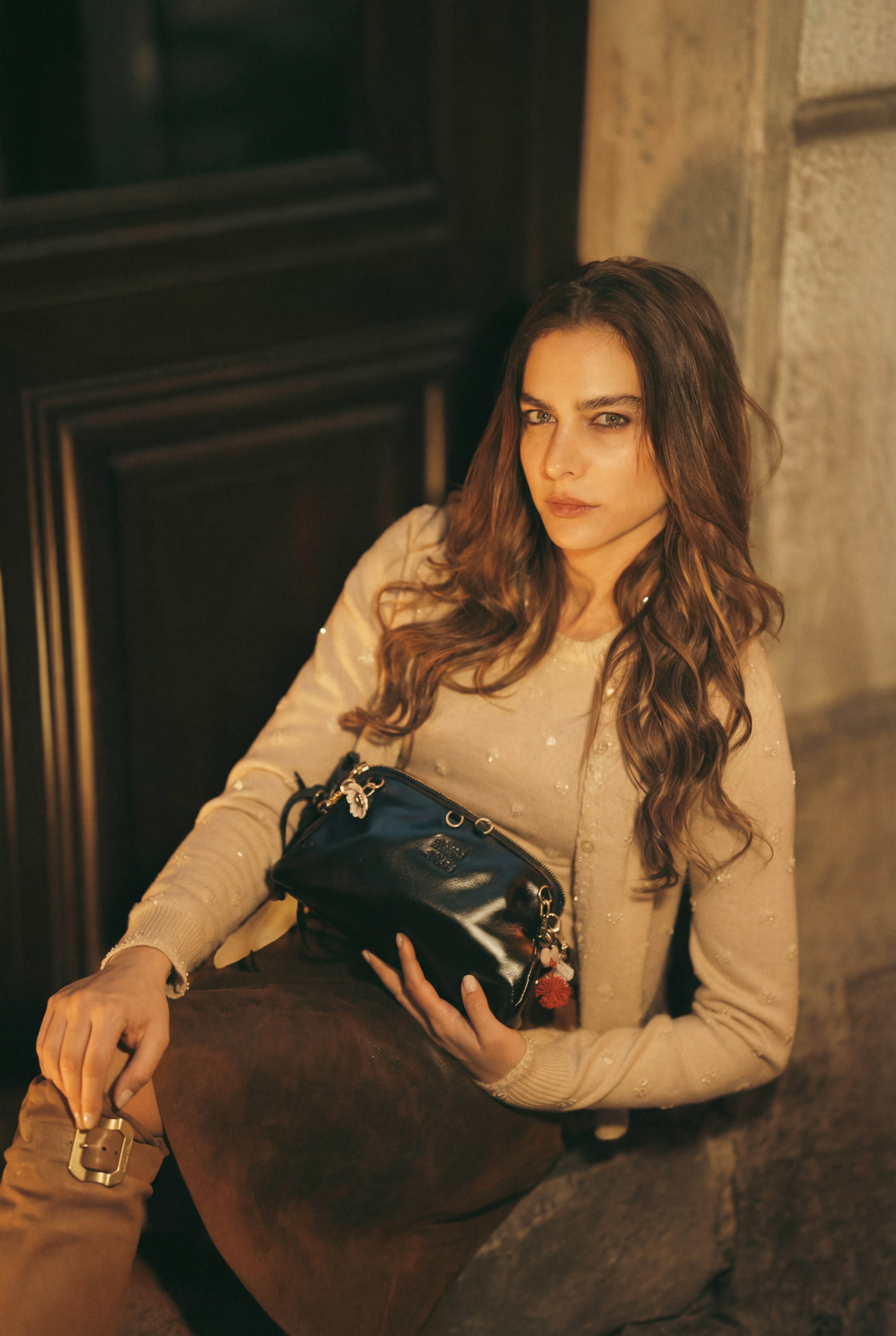 A woman holding a handbag sits outside at night.