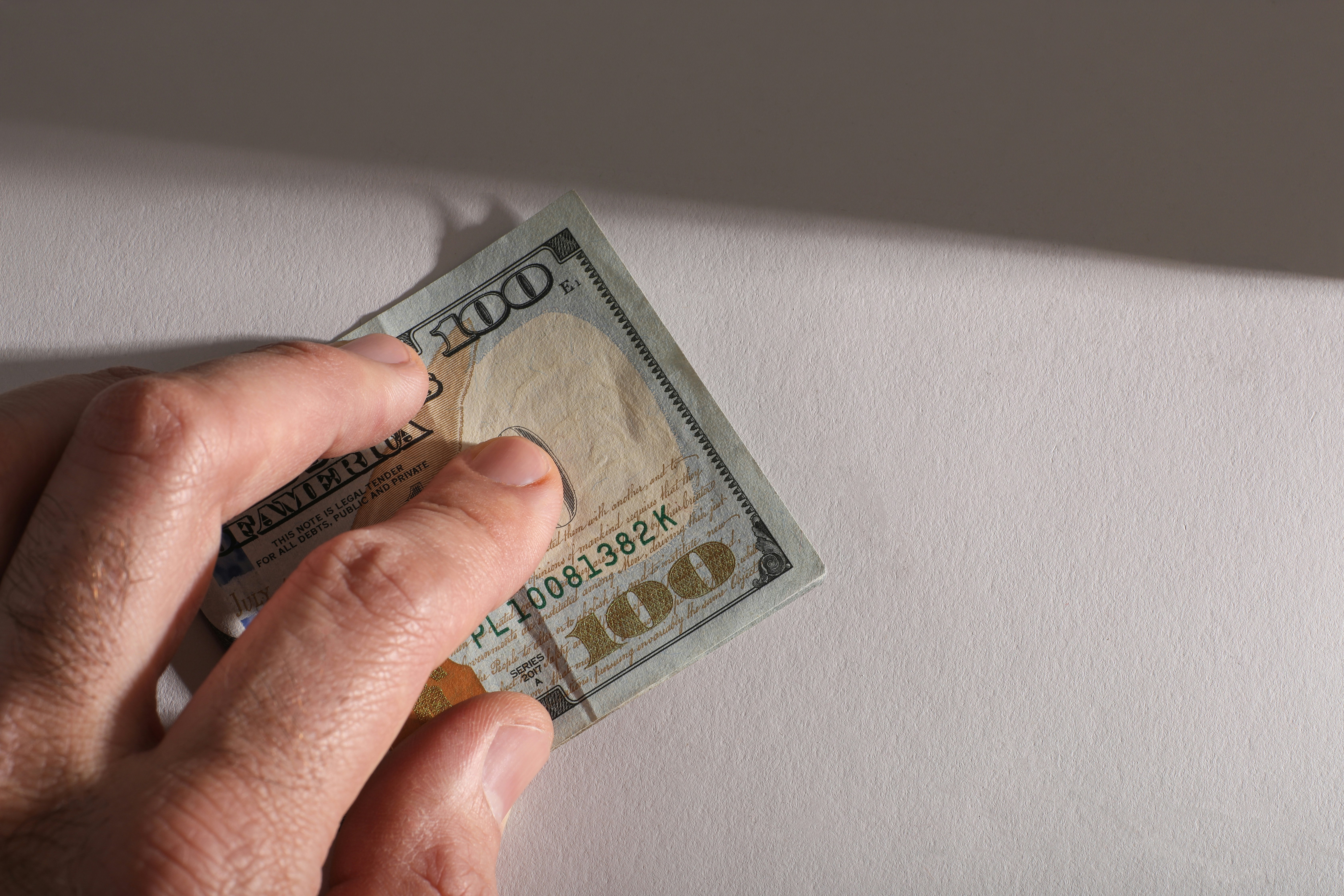 Hand holding a one hundred dollar bill