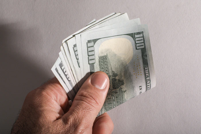 Fajo de billetes de cien dólares en la mano