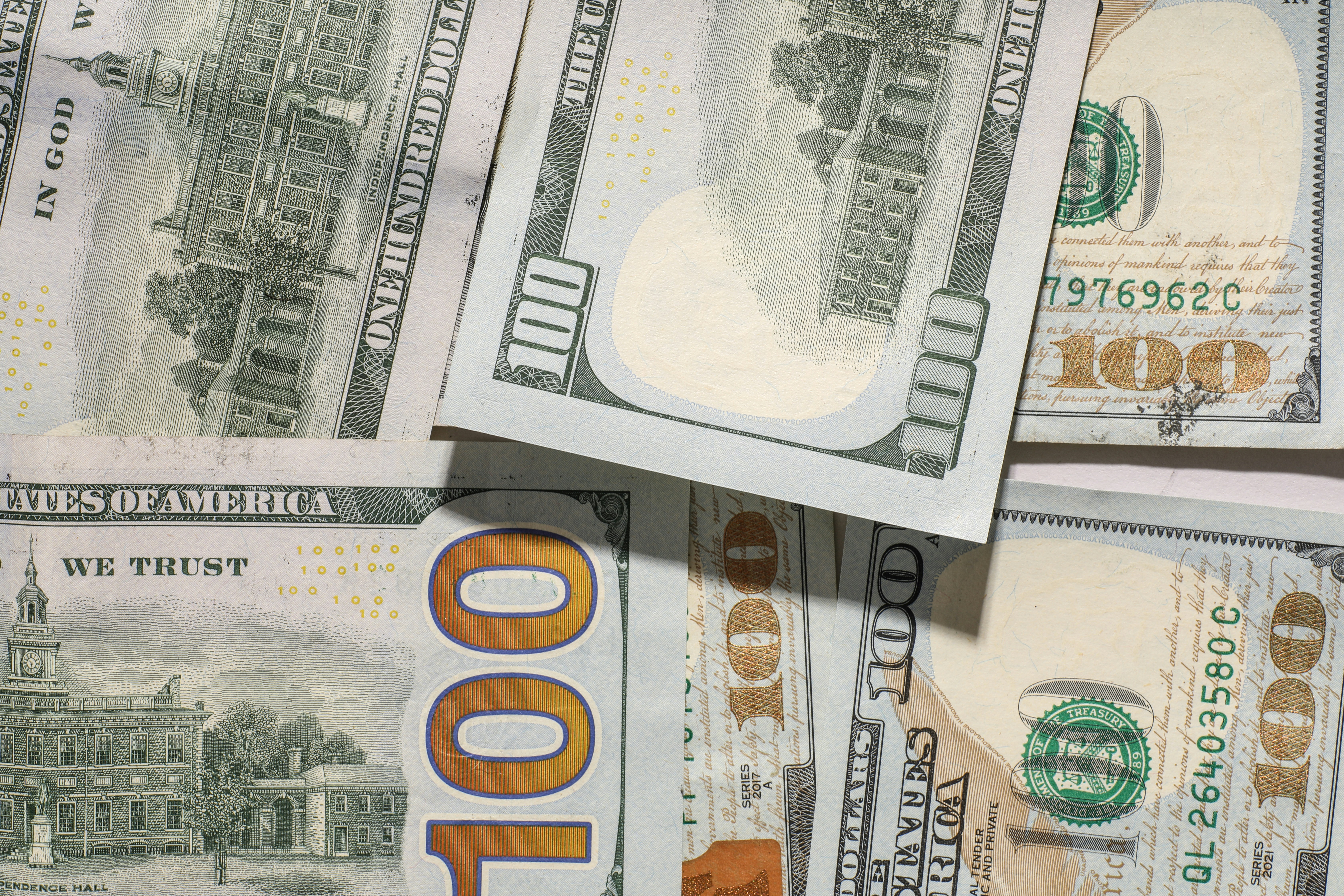 One hundred dollar bills scattered on a surface.