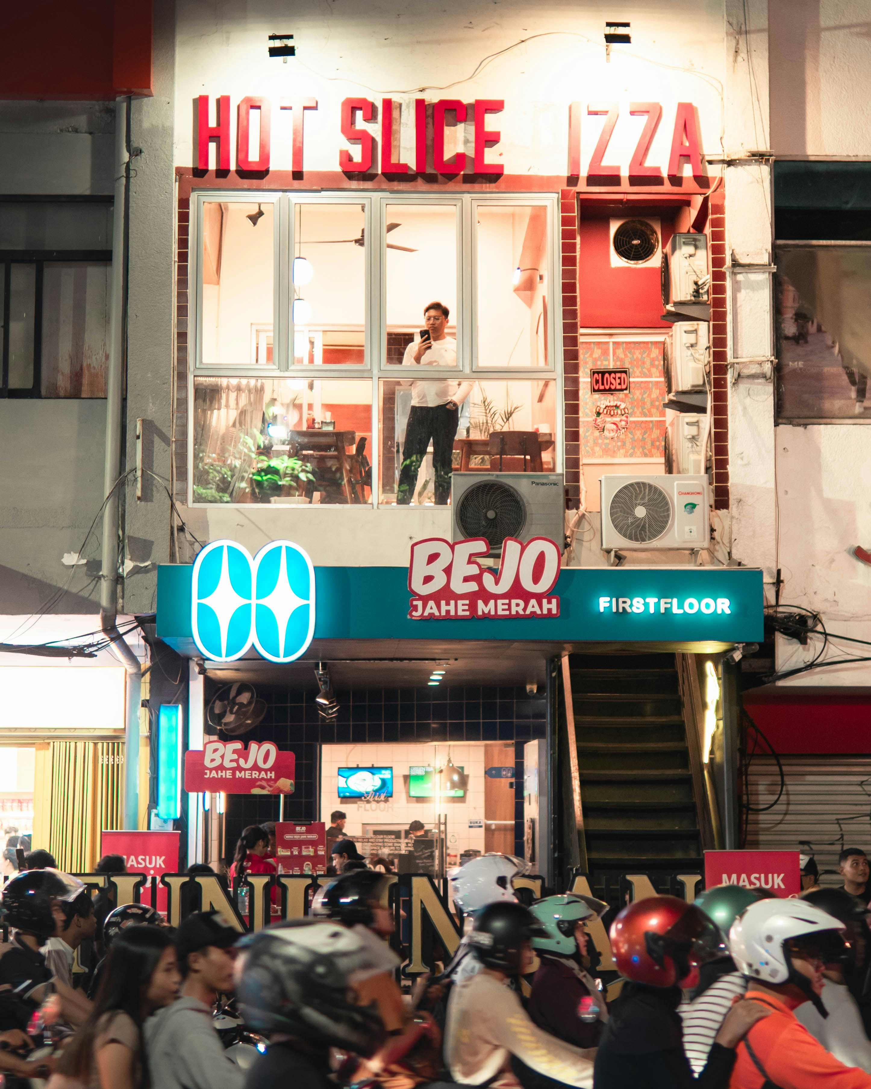 Pessoas de motocicleta do lado de fora de uma pizzaria à noite