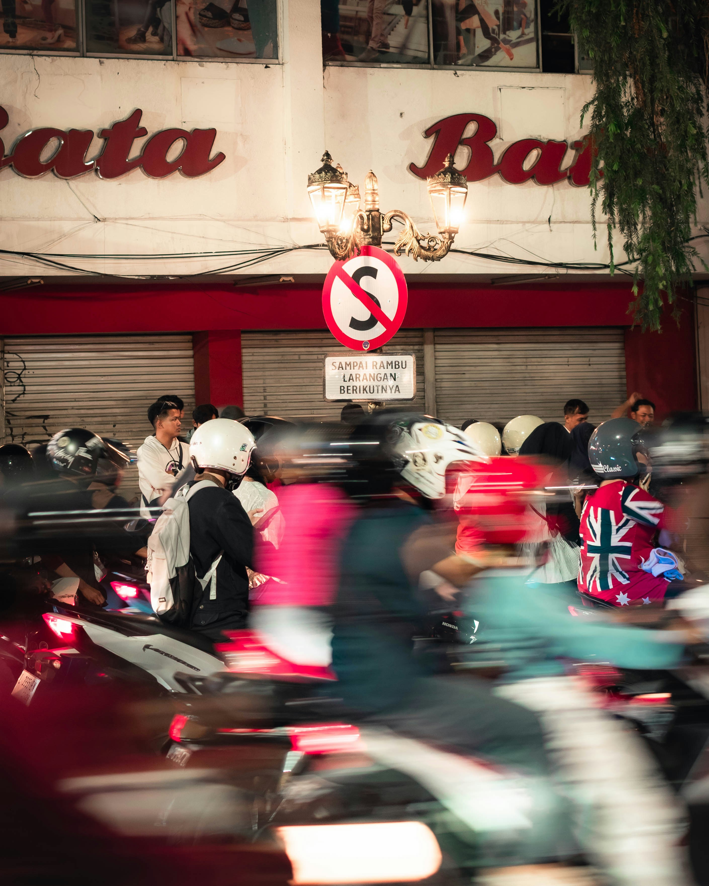 Sepeda motor bergerak di jalan yang sibuk di malam hari.