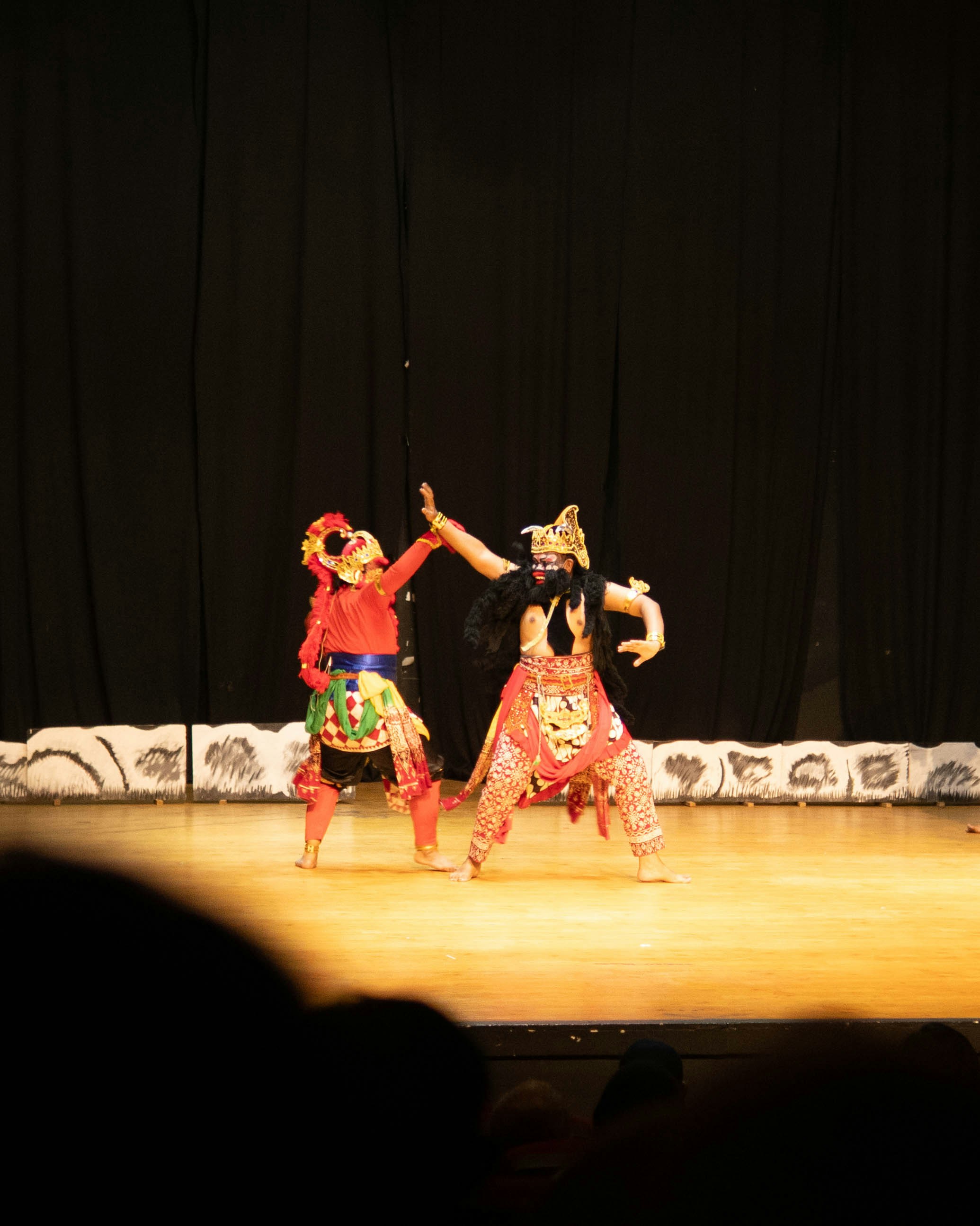 Dois dançarinos com trajes tradicionais se apresentam no palco.