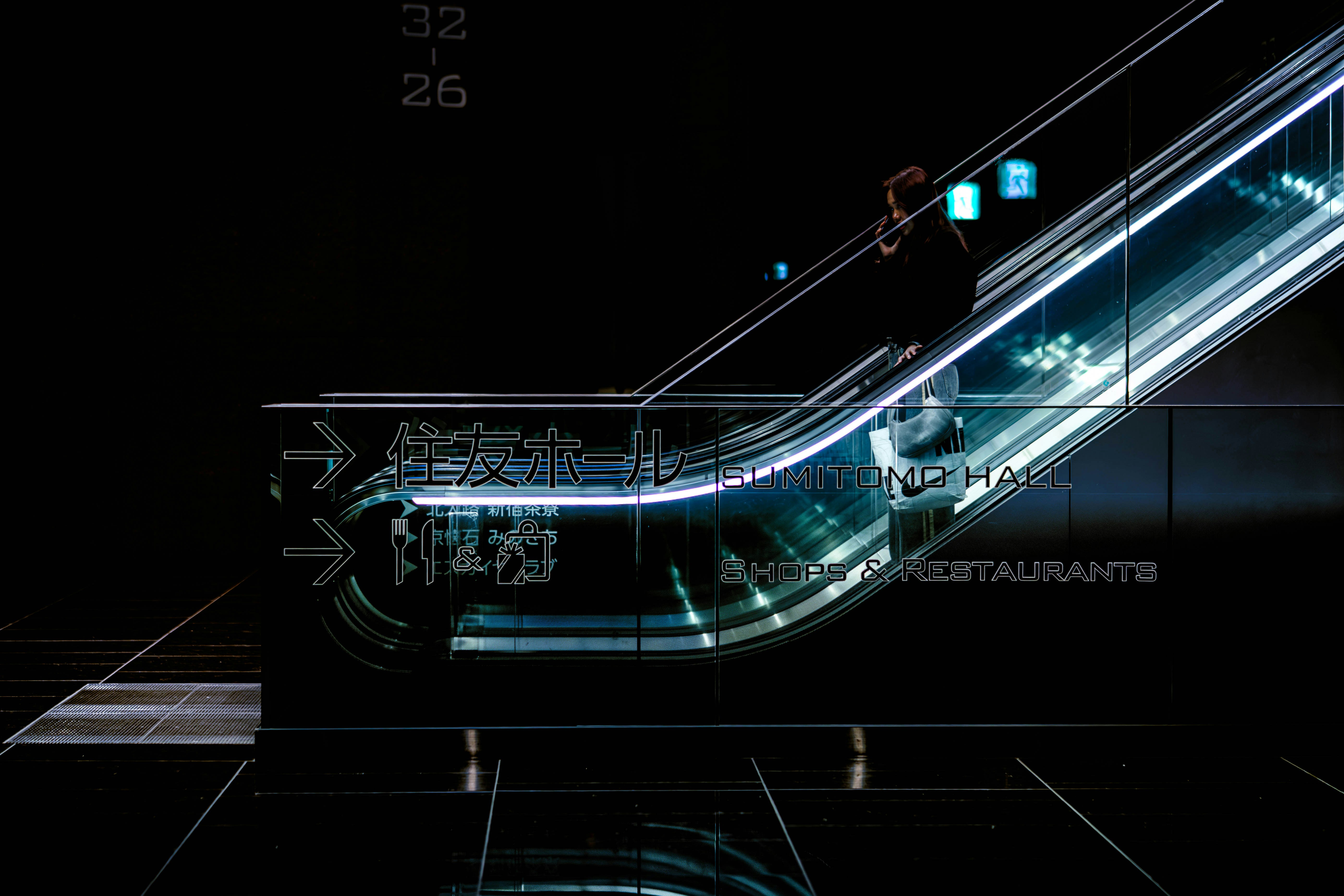 Escalator with futuristic digital signage in dark setting.