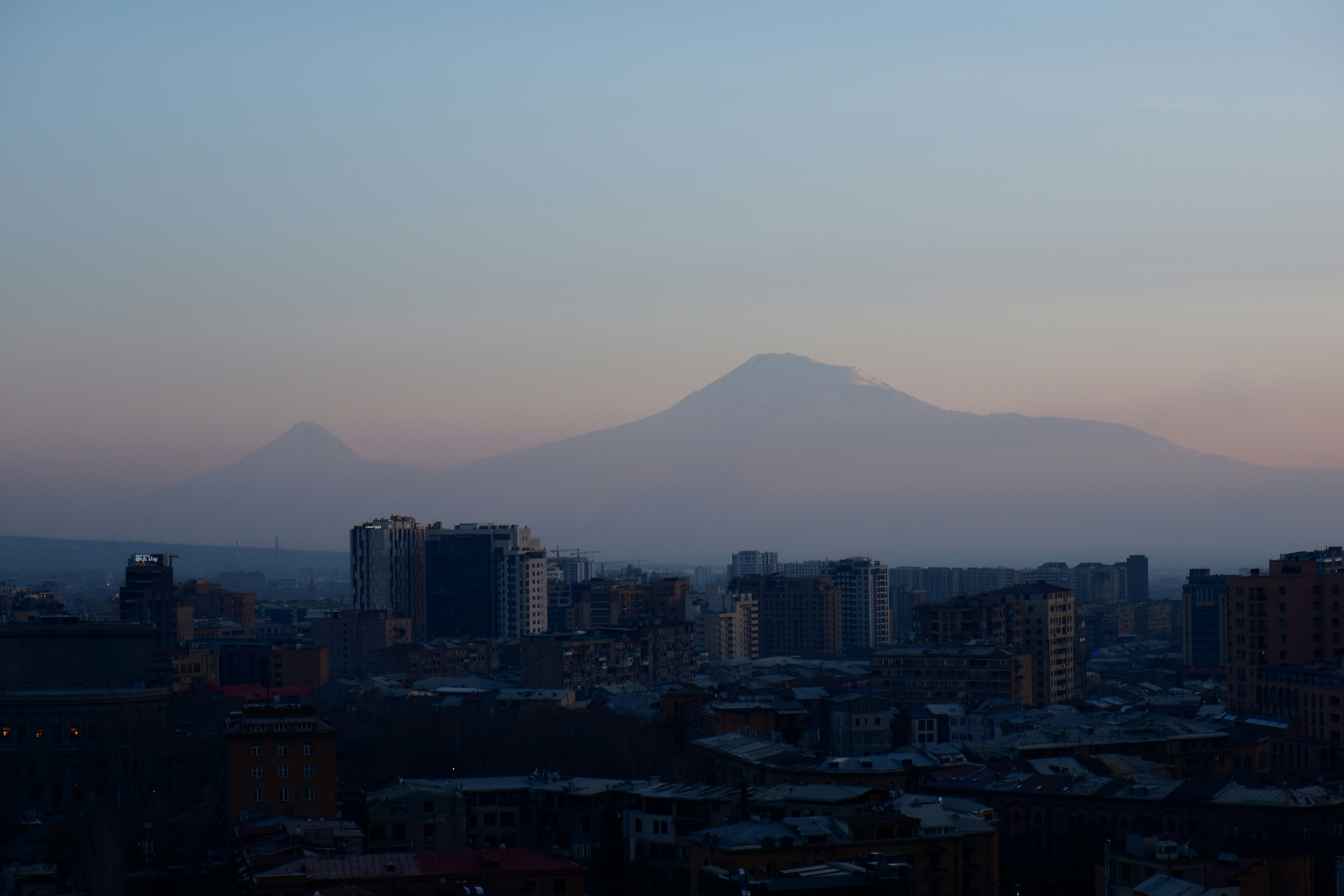 City skyline with mountains in the background at dusk