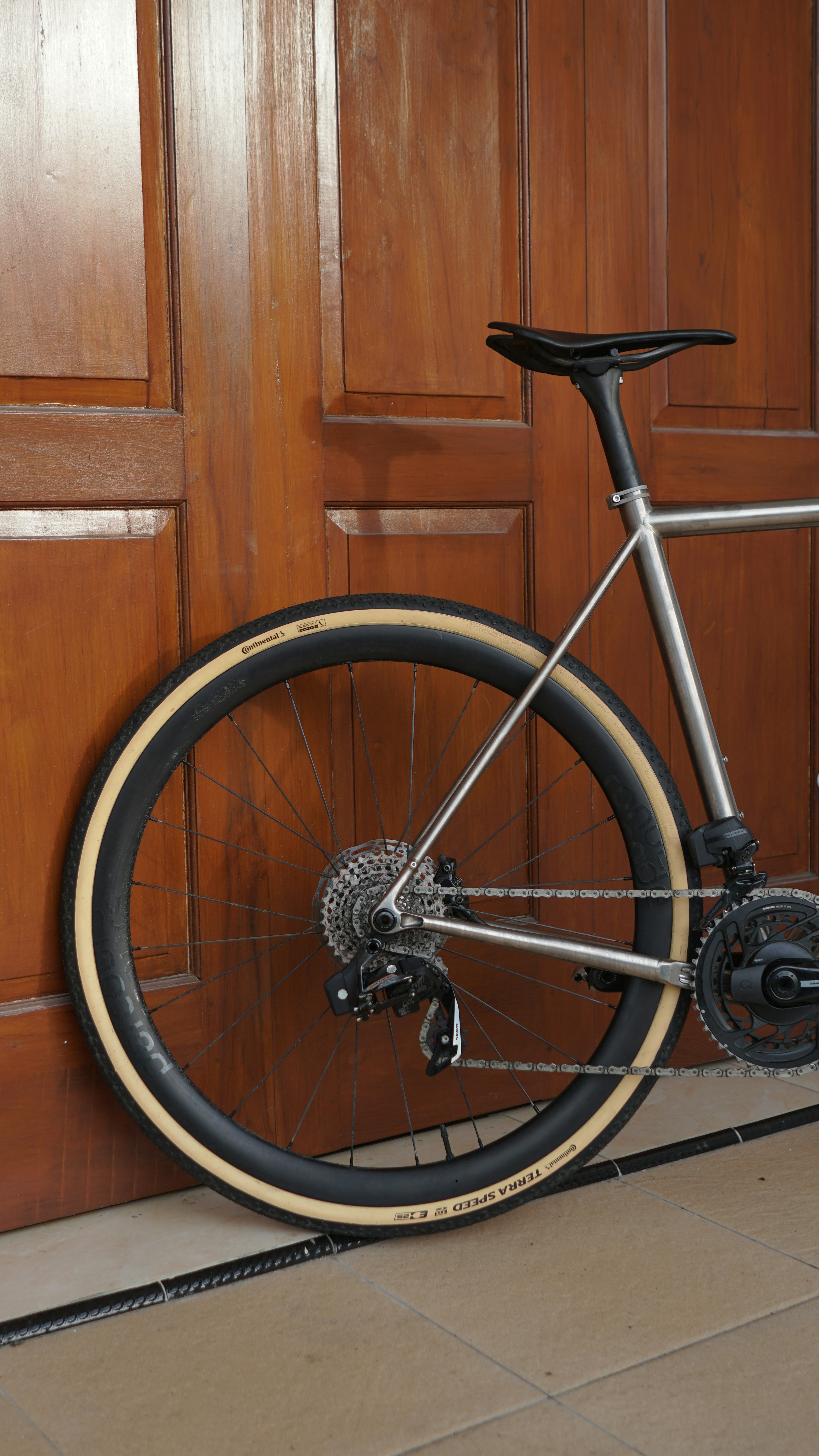 Silver bicycle leaning against a wooden door.