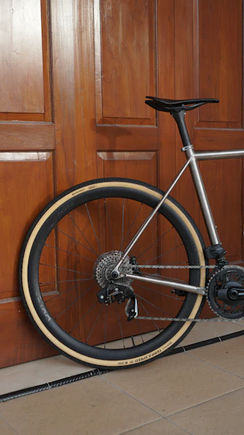 Silver bicycle leaning against a wooden door.
